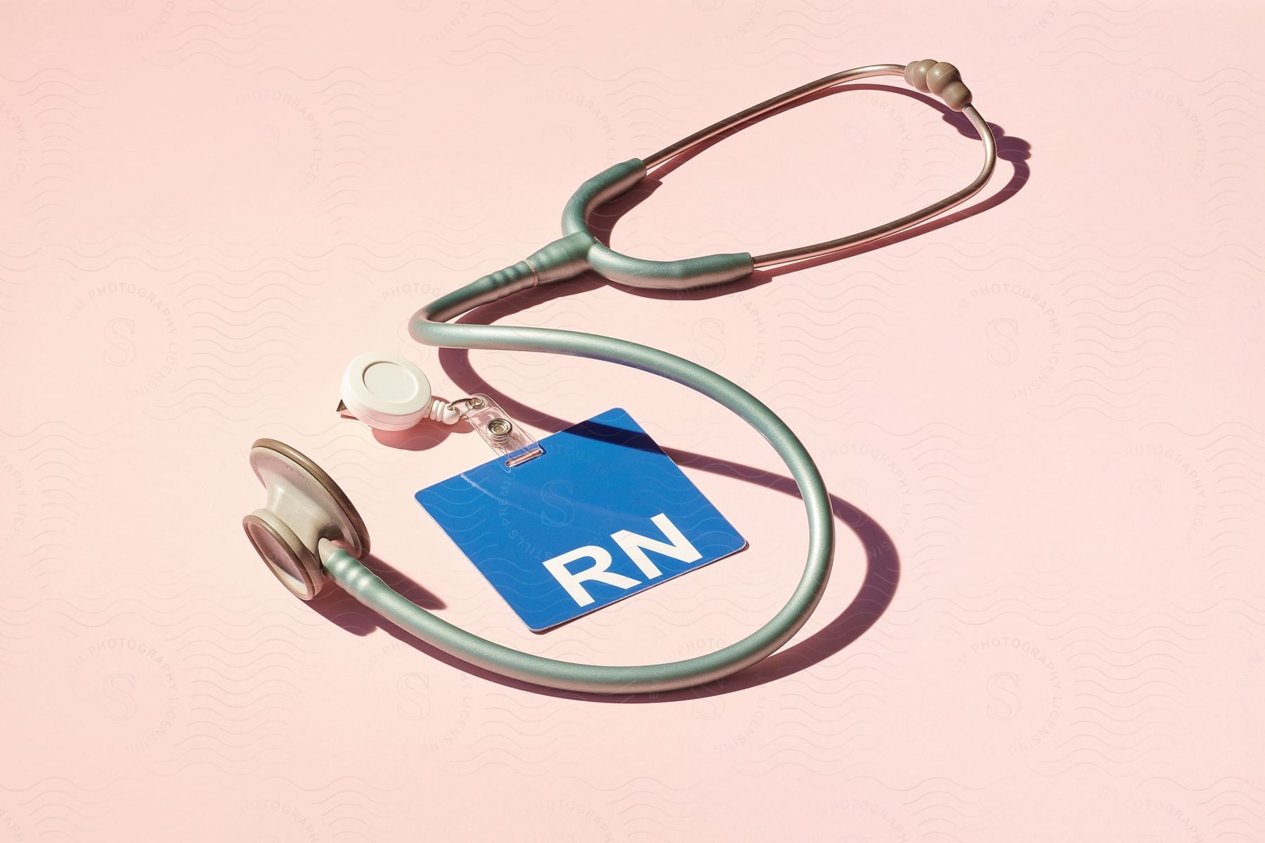 A name tag and stethoscope for a nurse on a pink background