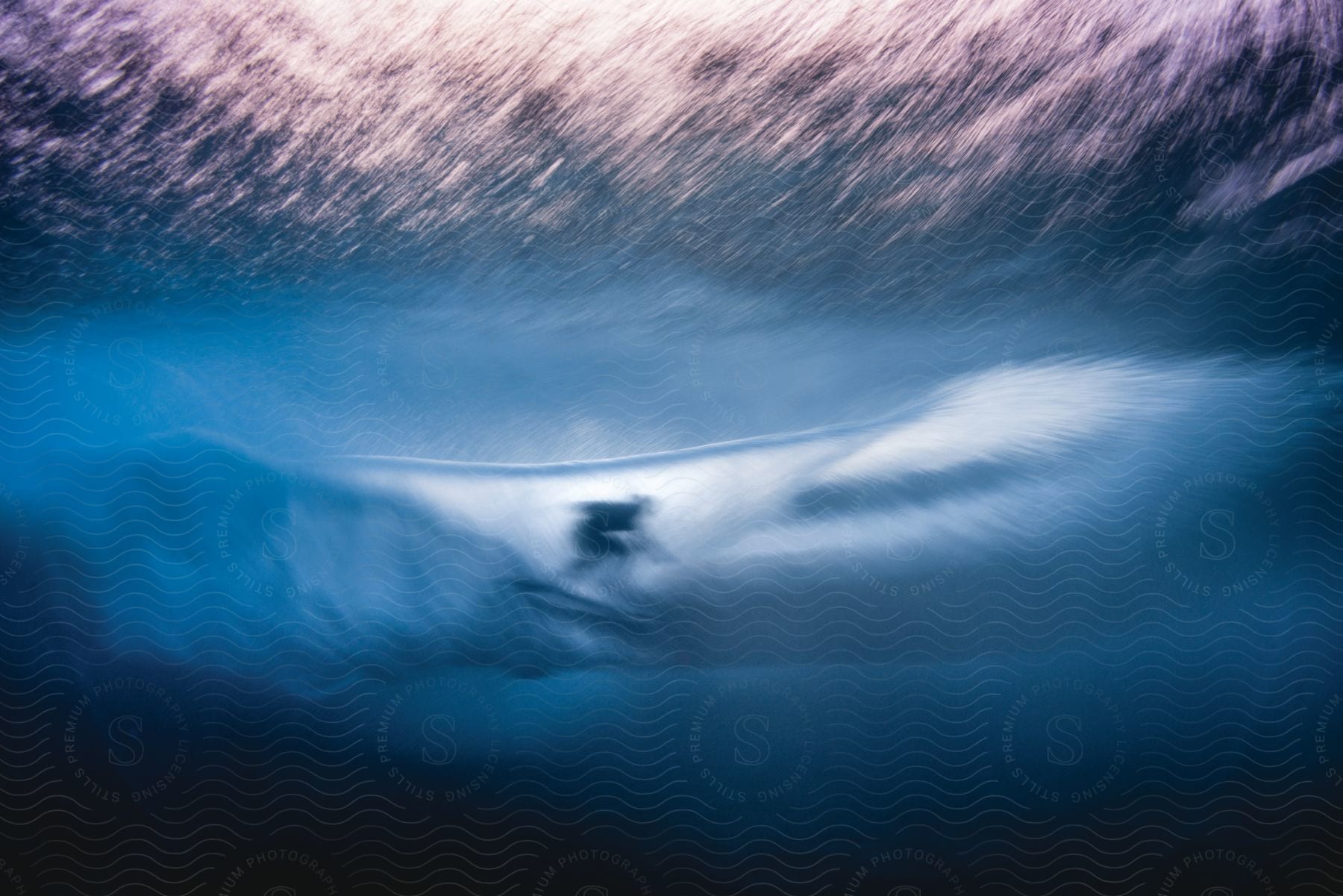 A surfer rides a wave in the ocean seen from underwater