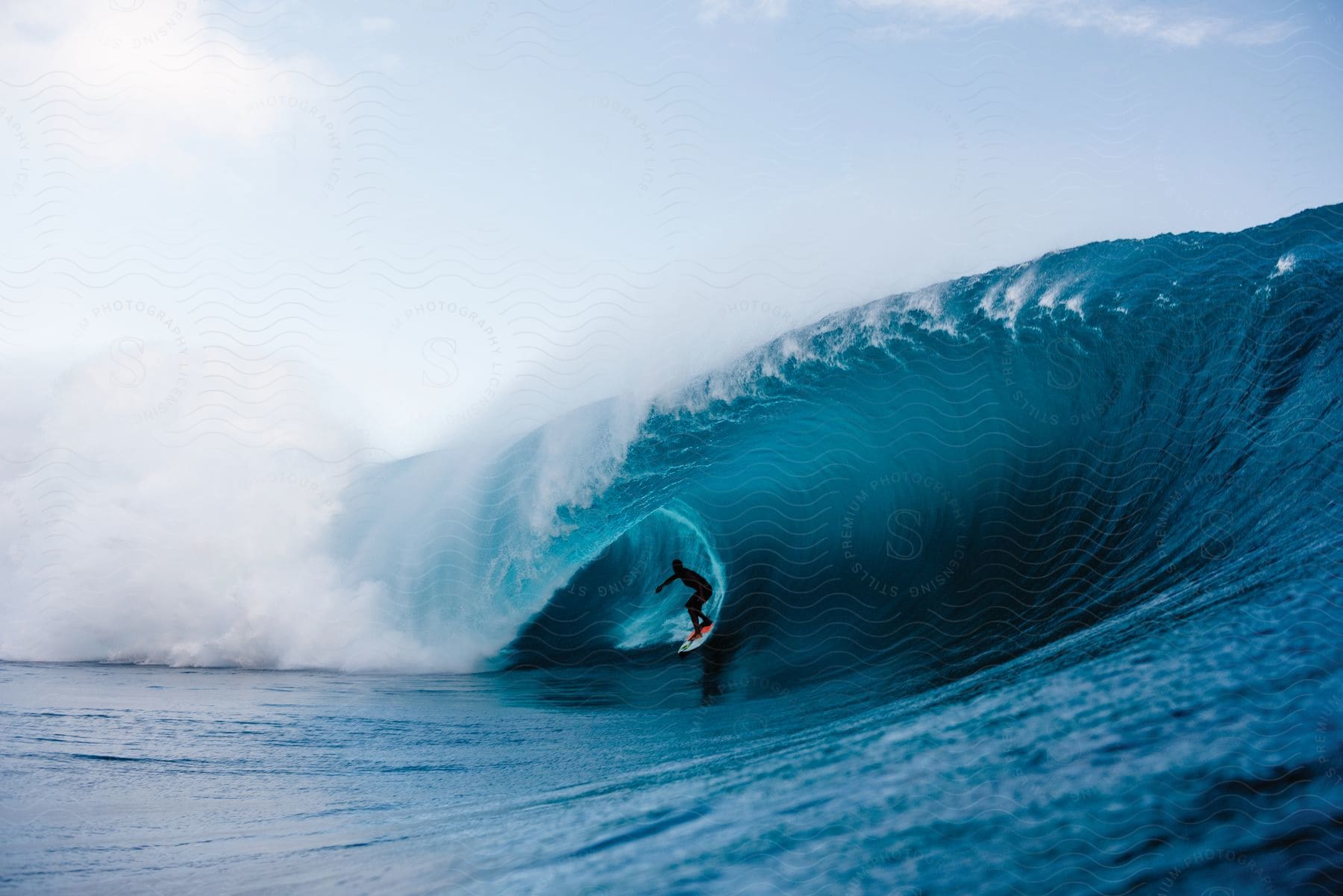 A person rides a wave in the ocean under the sun