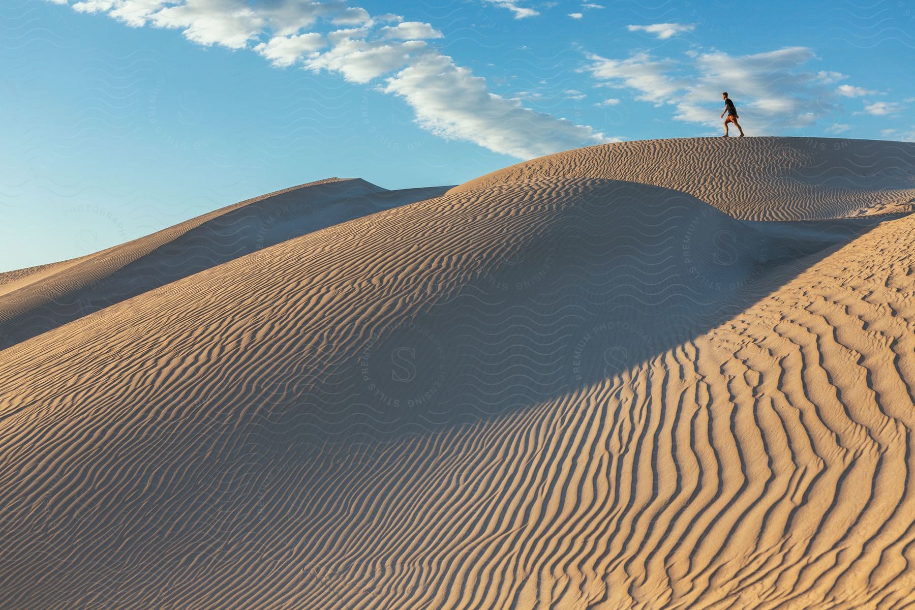 A person walks across sand dunes in a desert
