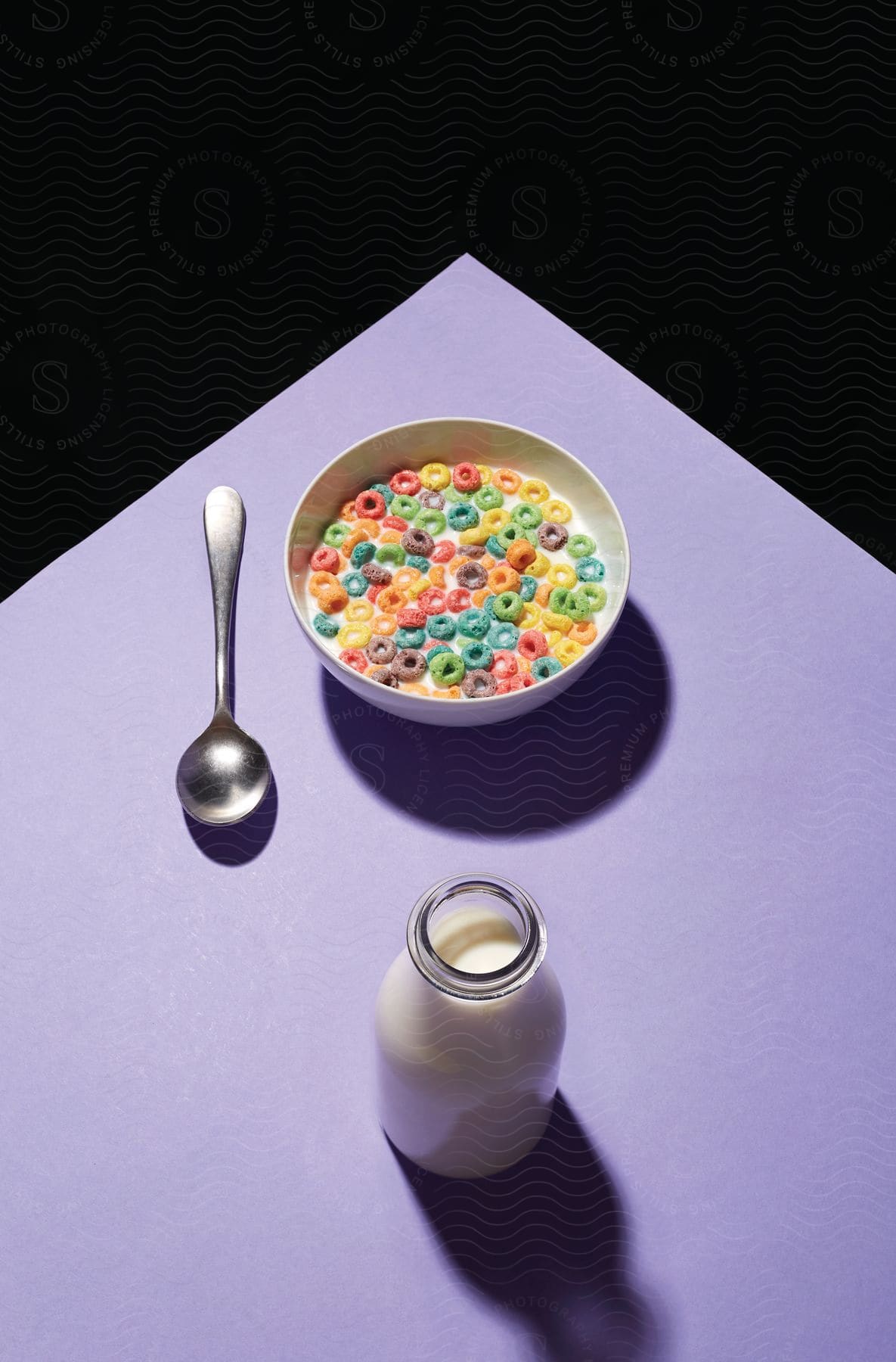 A bowl of fruity loops with milk on a purple table