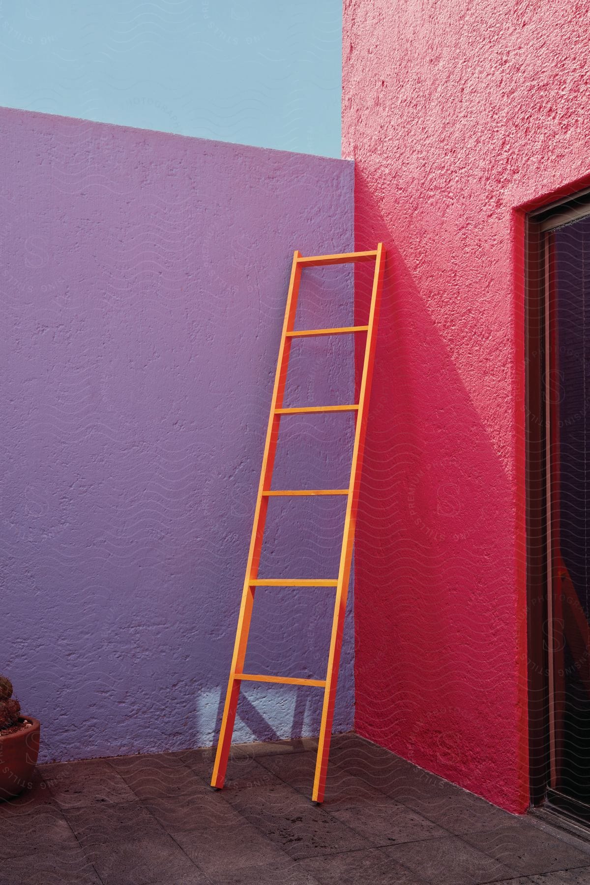 A wooden ladder placed on a wall painted red blue and purple