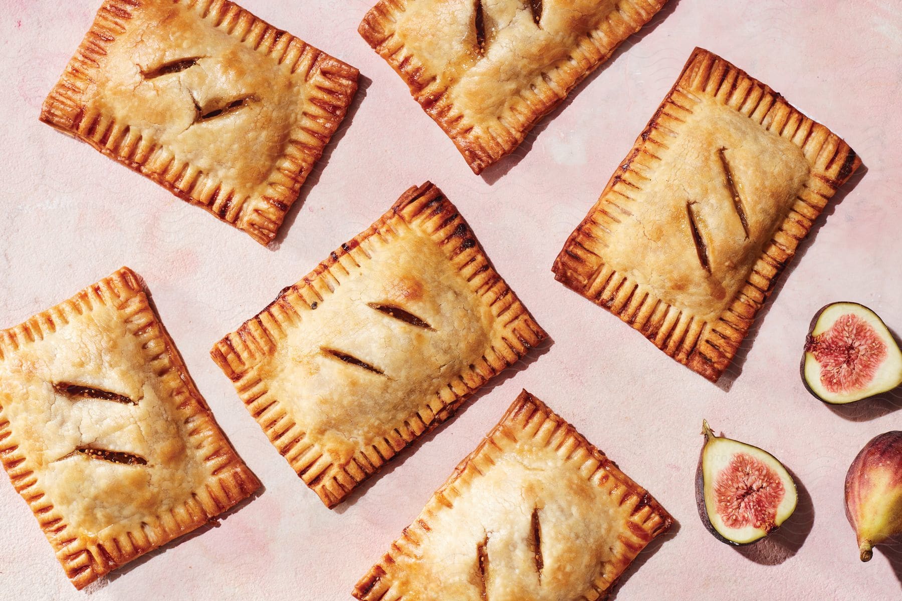 A Series Of Biscuits Placed On A Pink Surface Next To A Slice Of Fruit