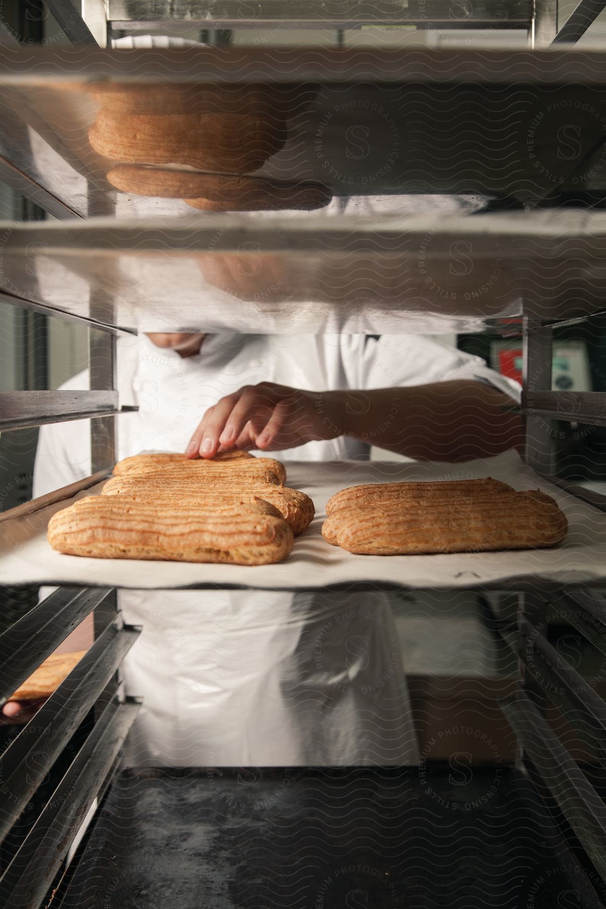 A chef touches some loaf of bread in a kitchen