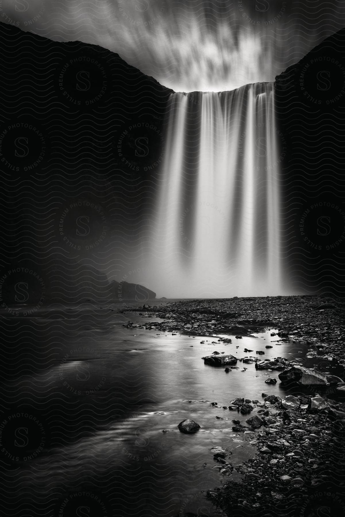 A waterfall flowing into a river in black and white