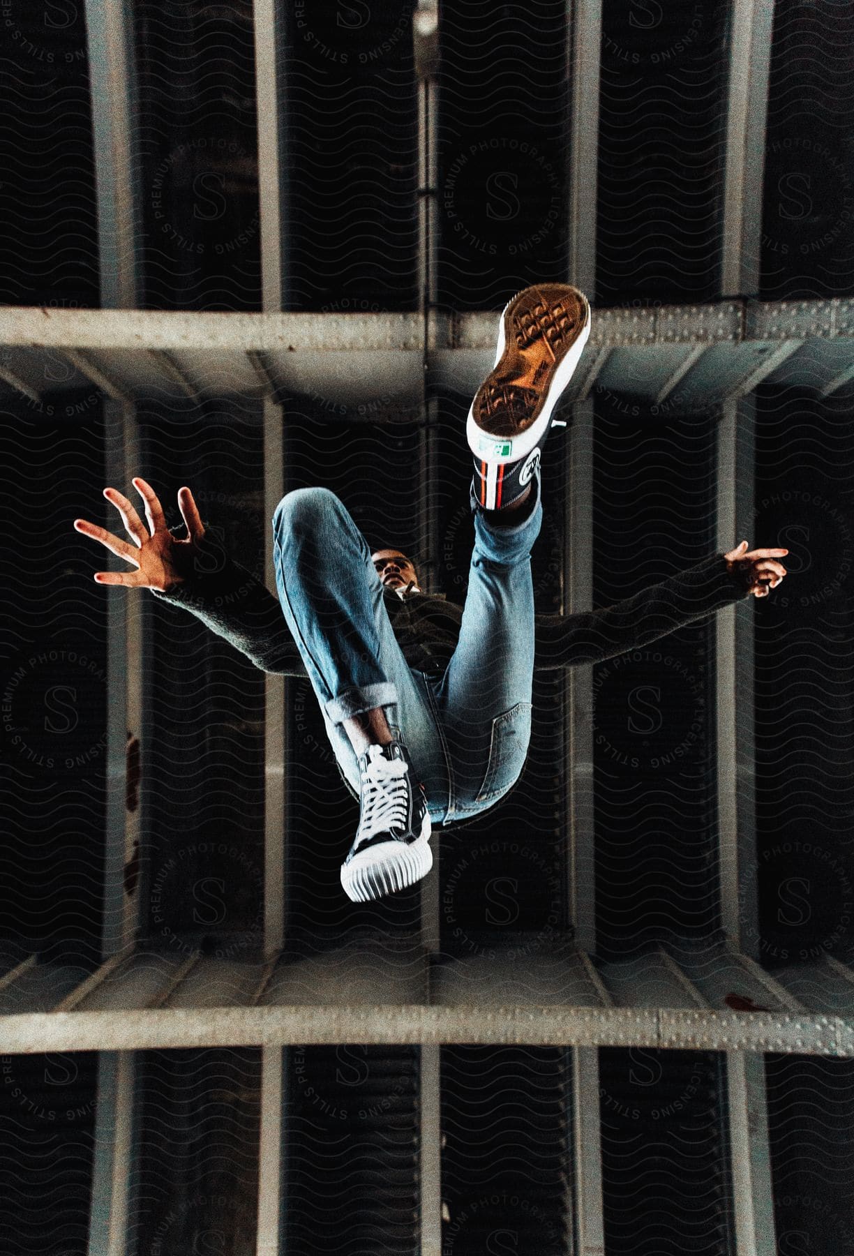 A man in his 20s or 30s is jumping and doing parkour outdoors at night time