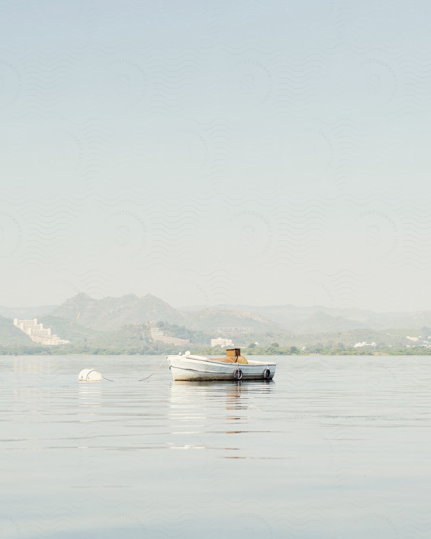 A small canoe in a white scene with mountains in the background