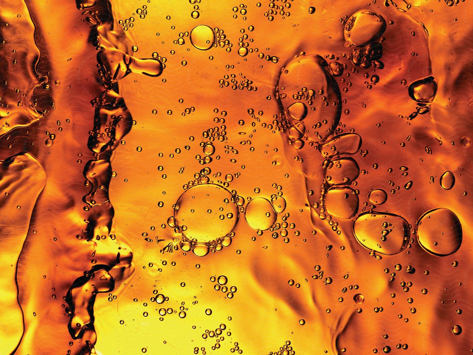 Bubble formations in various shapes and sizes suspended in an amber liquid