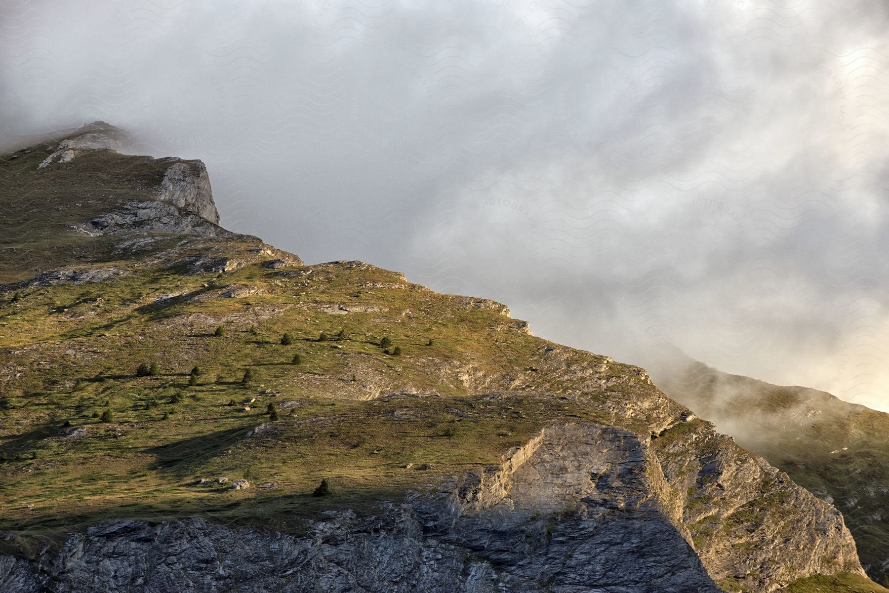 A green mountain cliff dropping into clouds