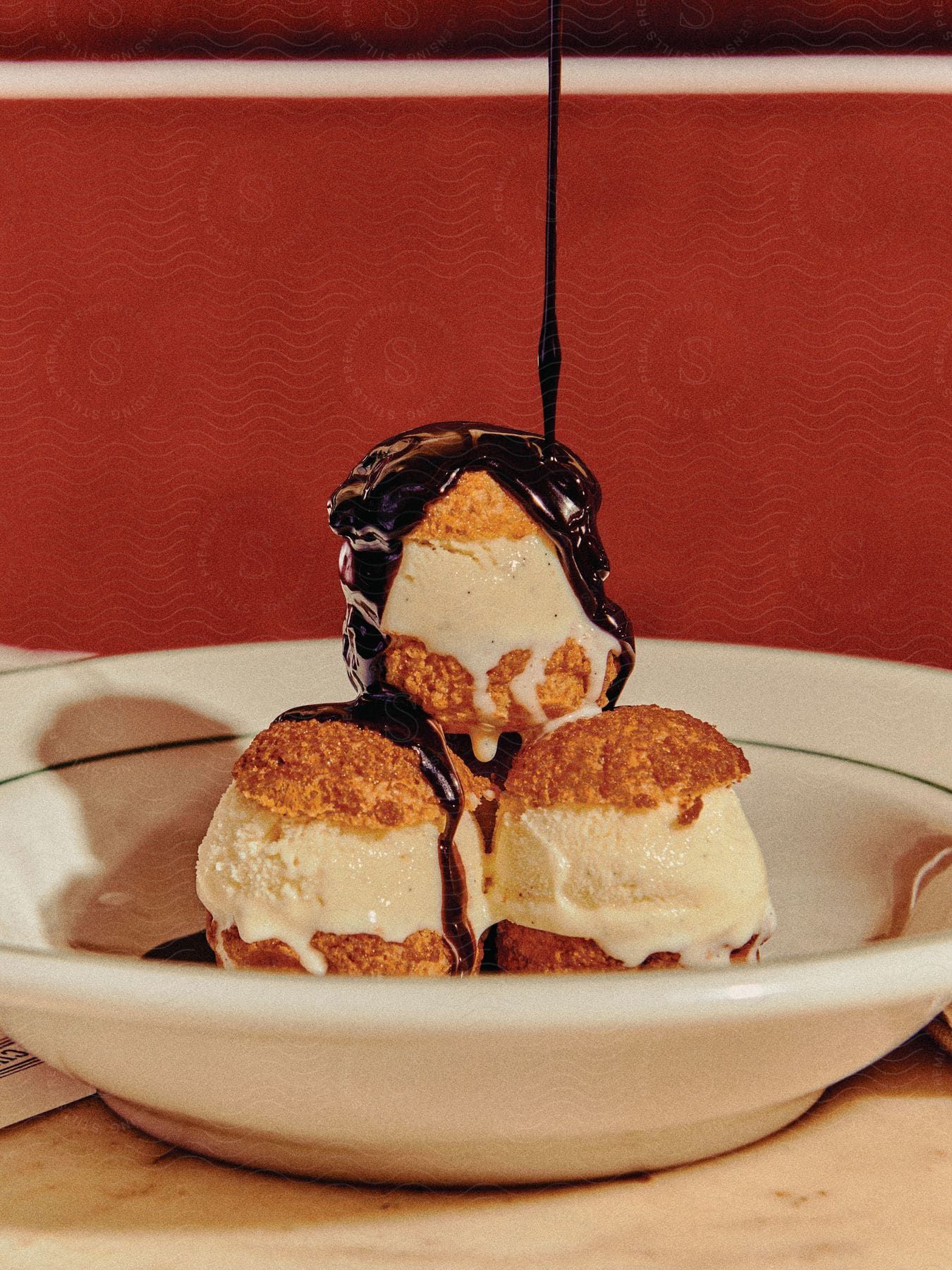 Ice cream puffs with chocolate sauce being drizzled over them