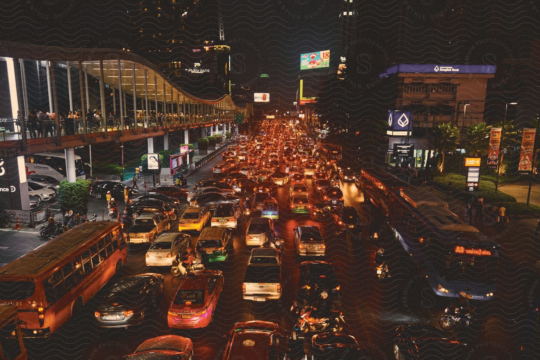 A busy downtown streetscape at night filled with vehicles people and illuminated buildings and billboards