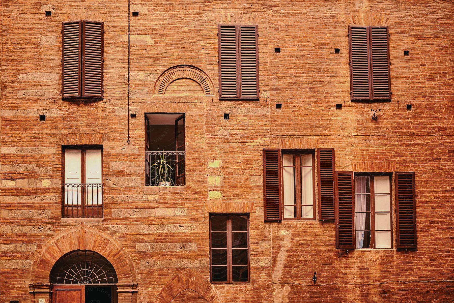 Oddly placed shuttered windows on the side of a brown venetianstyle building