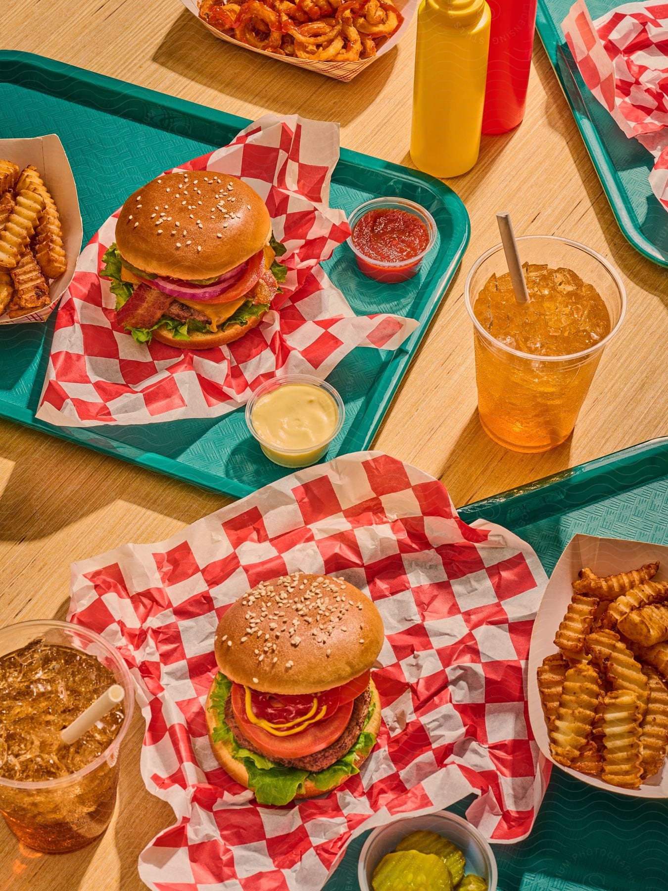 Hamburgers french fries iced drinks and condiments on a table