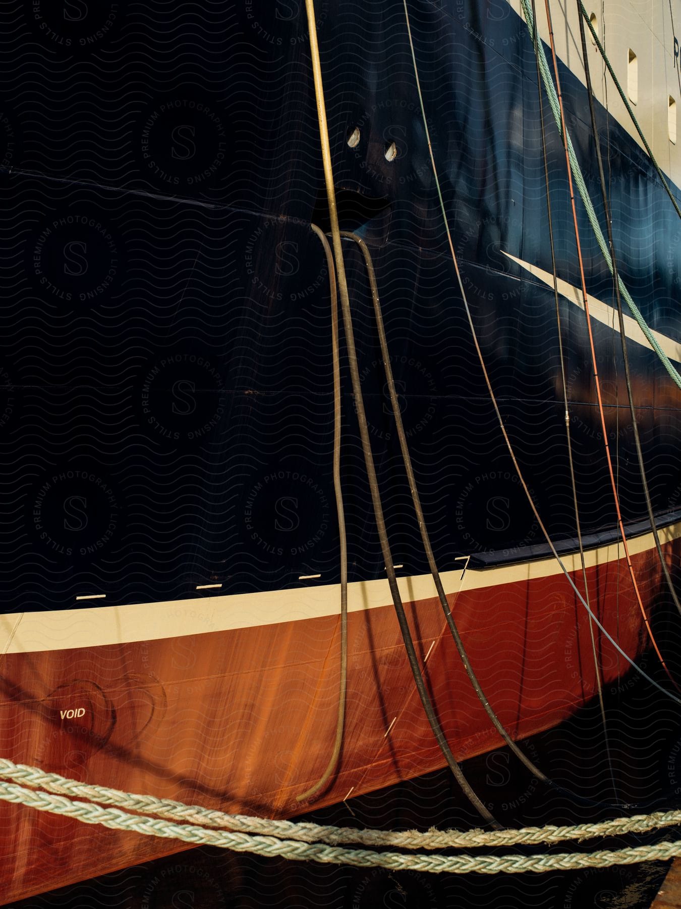 A close up on the side of a large boat with many ropes coming off of it