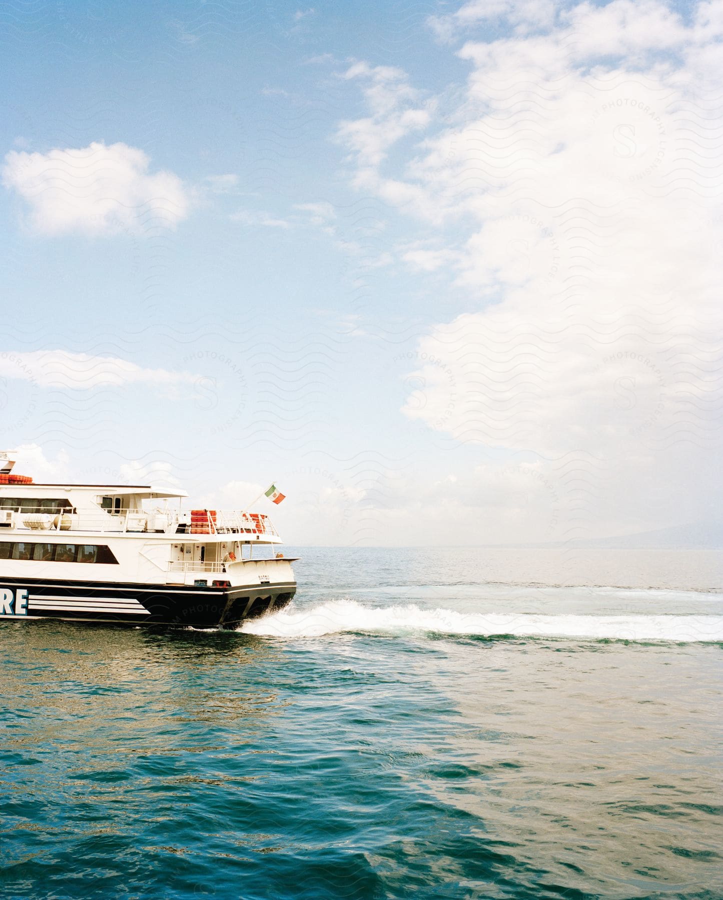 A ferry with a mexican flag sailing through the sea on a sunny day