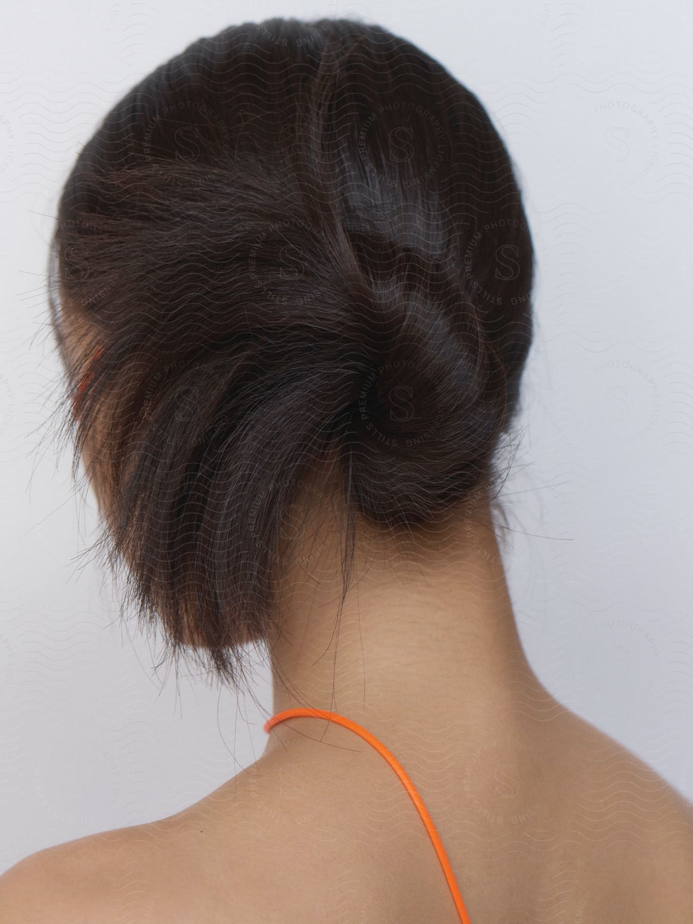 A woman with a bun in her hair wearing an orange top