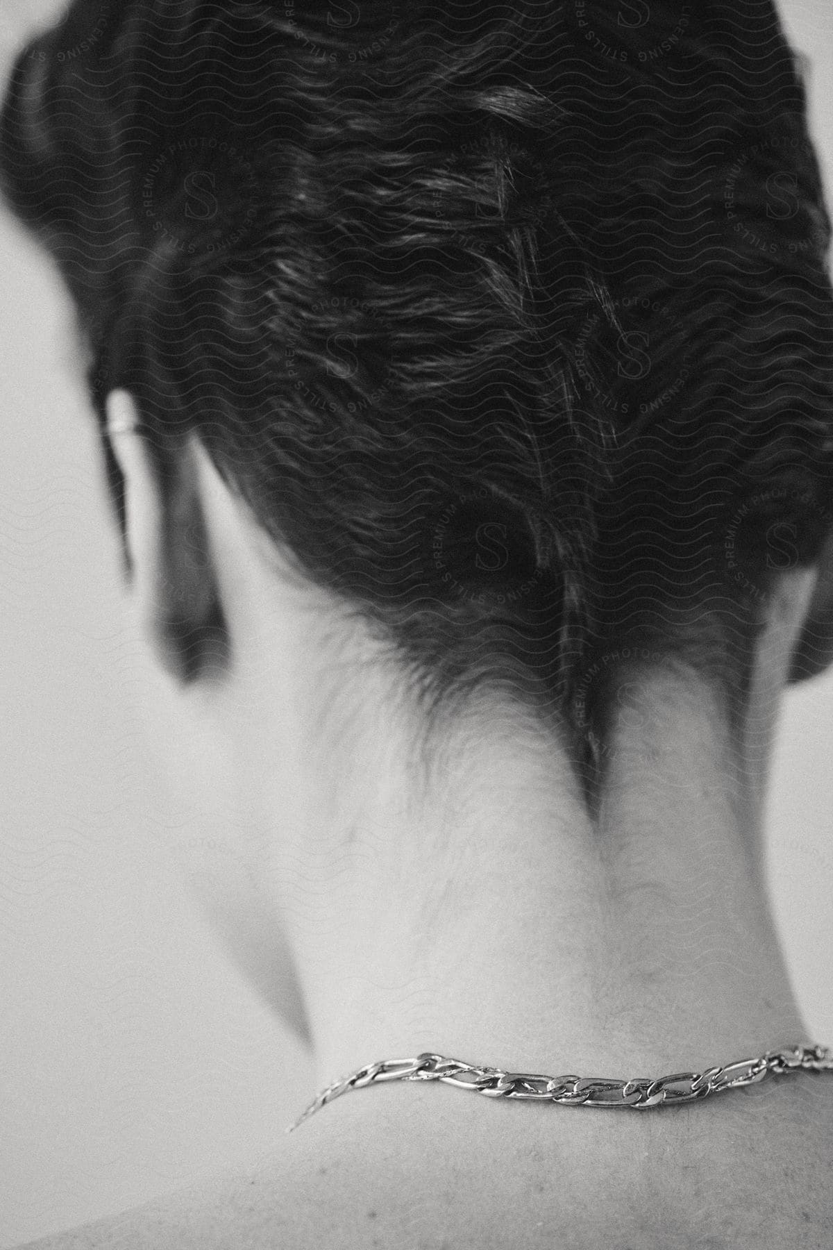 A persons head seen from the back wearing a necklace in a black and white image