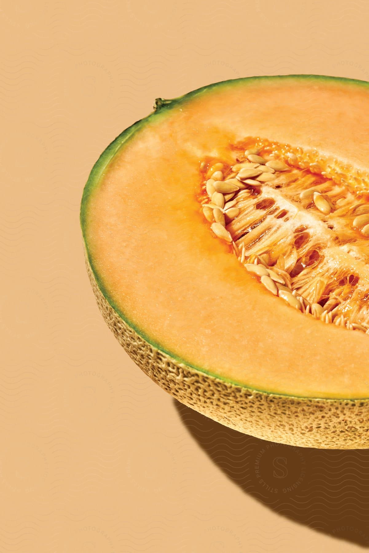 Close up of melon seeds inside a halved melon placed on a cream background