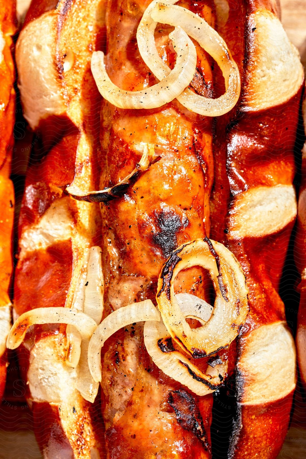 Closeup of a grilled coney dog on a pretzel bun with grilled onions