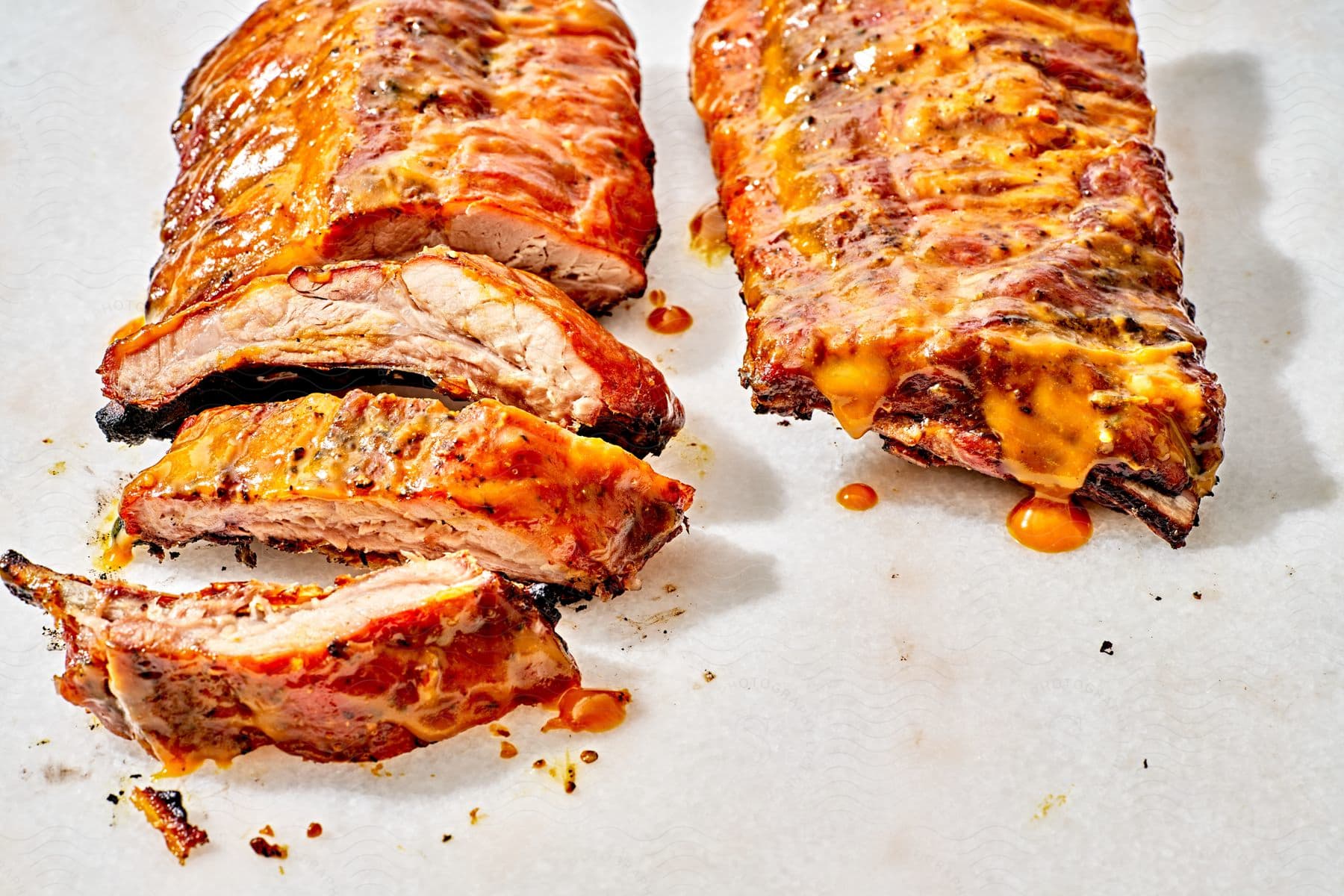 Stock photo of baby back ribs with yellow sauce on a white counter