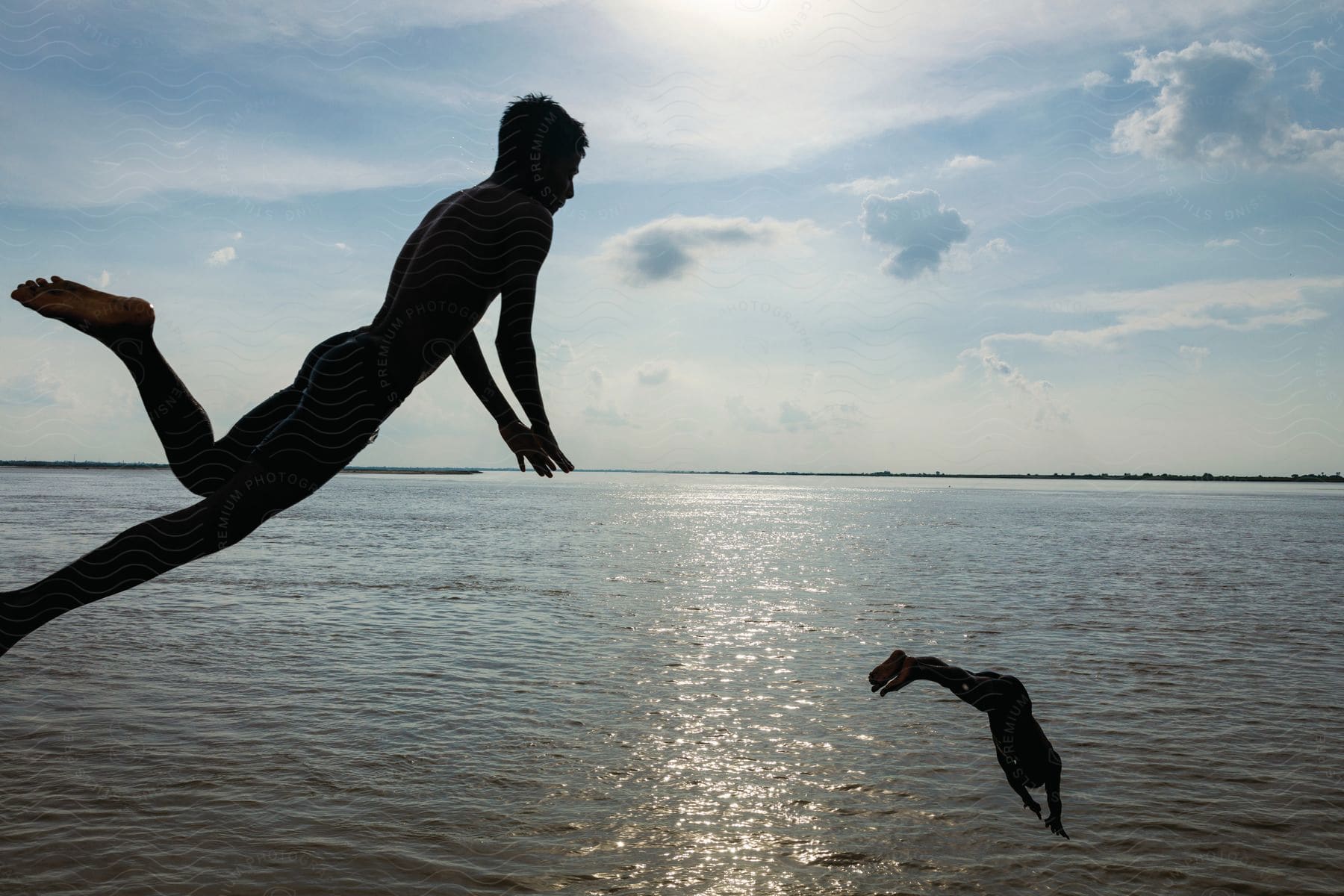 Two people diving into a body of water during the day