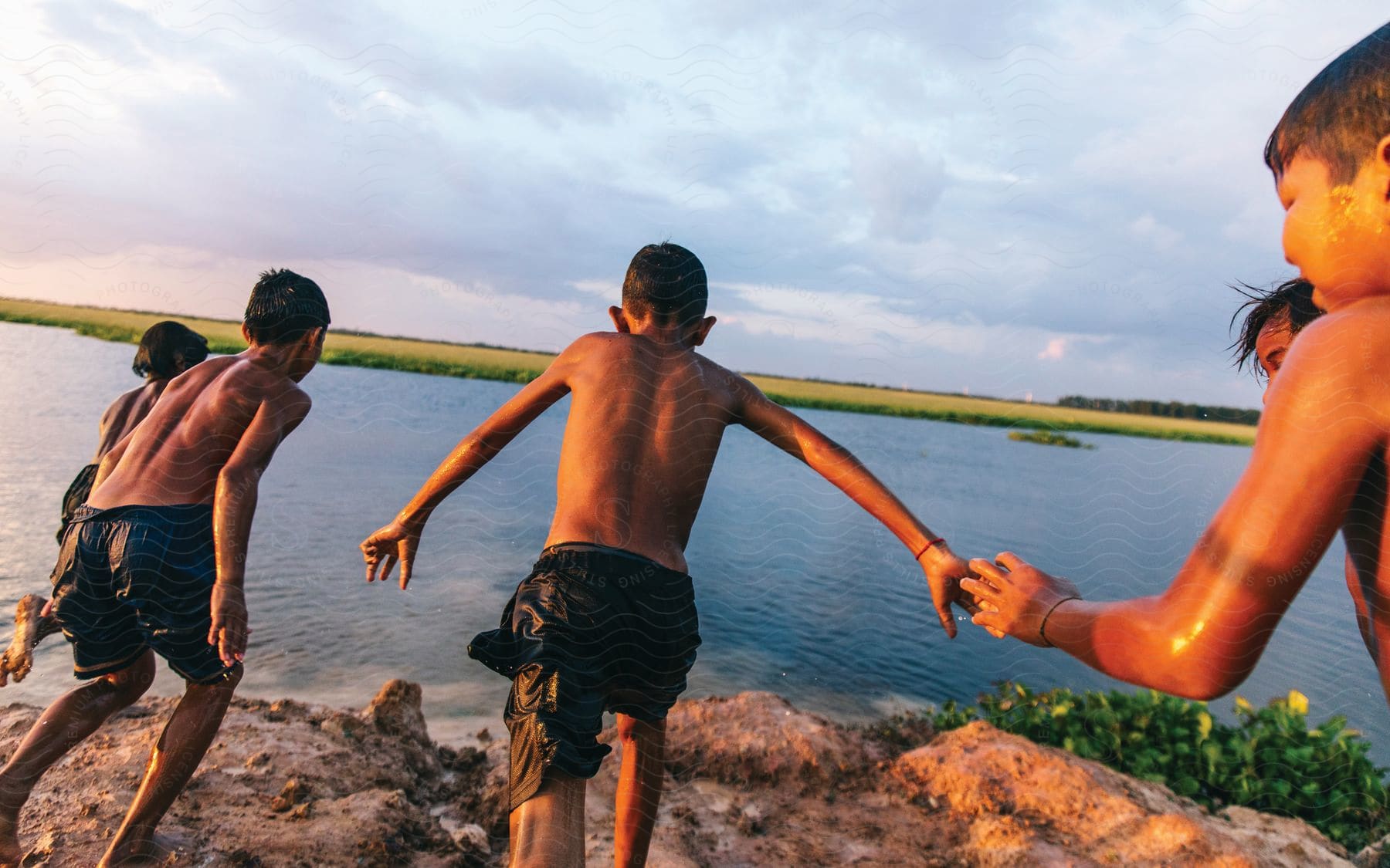 A group of boys preparing to jump off rocks into a lake