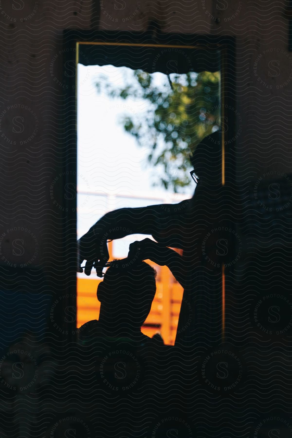 A man getting his hair cut in a salon looking at a mirror showing the colorful outdoors with his head in silhouette