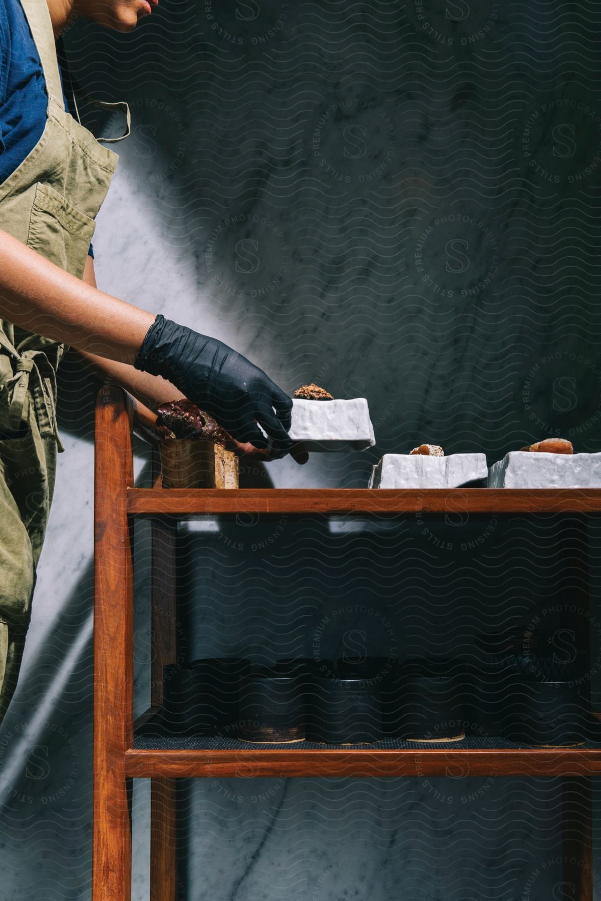 A woman is placing prepared food onto a table for further processing in the daytime