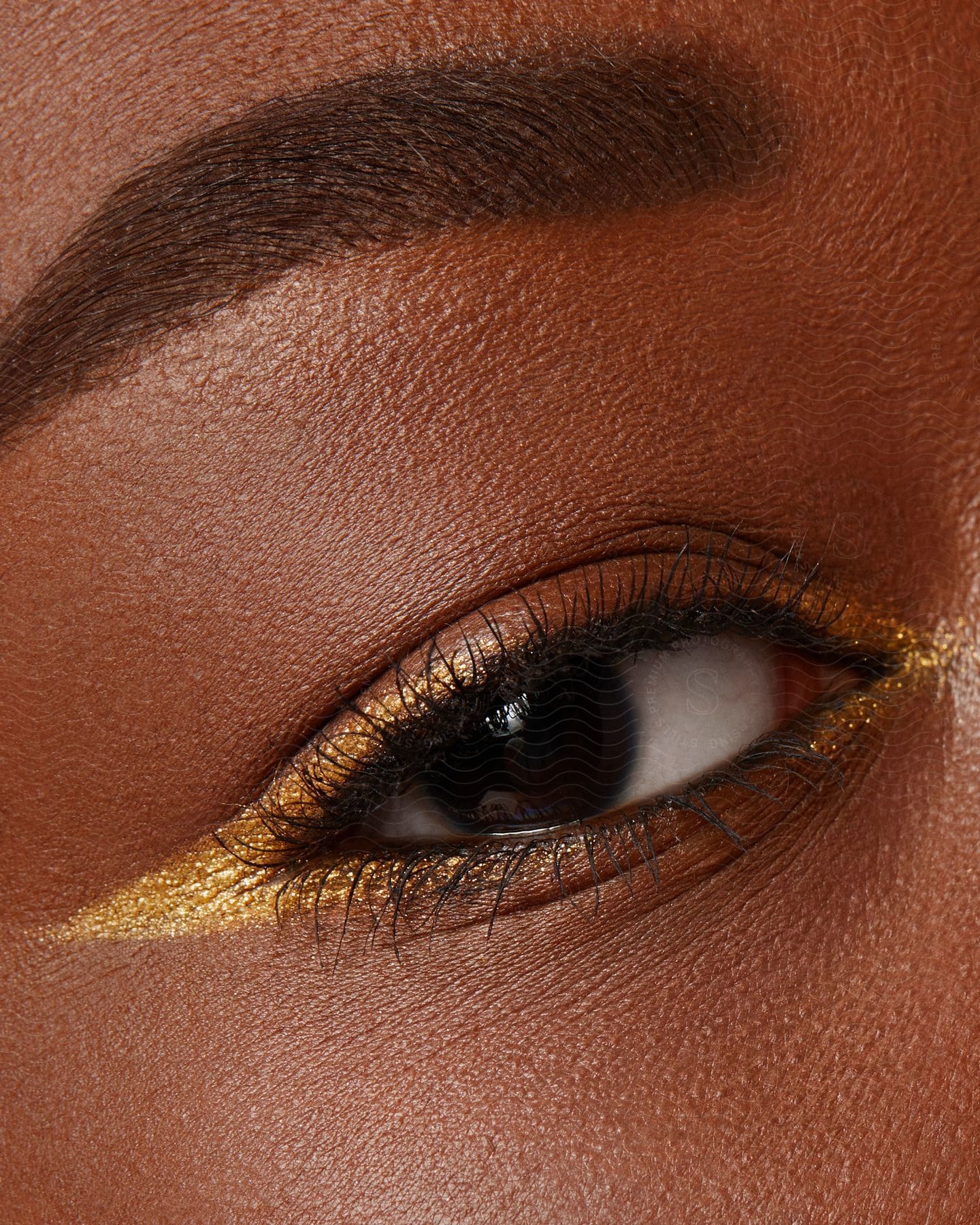 A black models eye with gold eyeliner