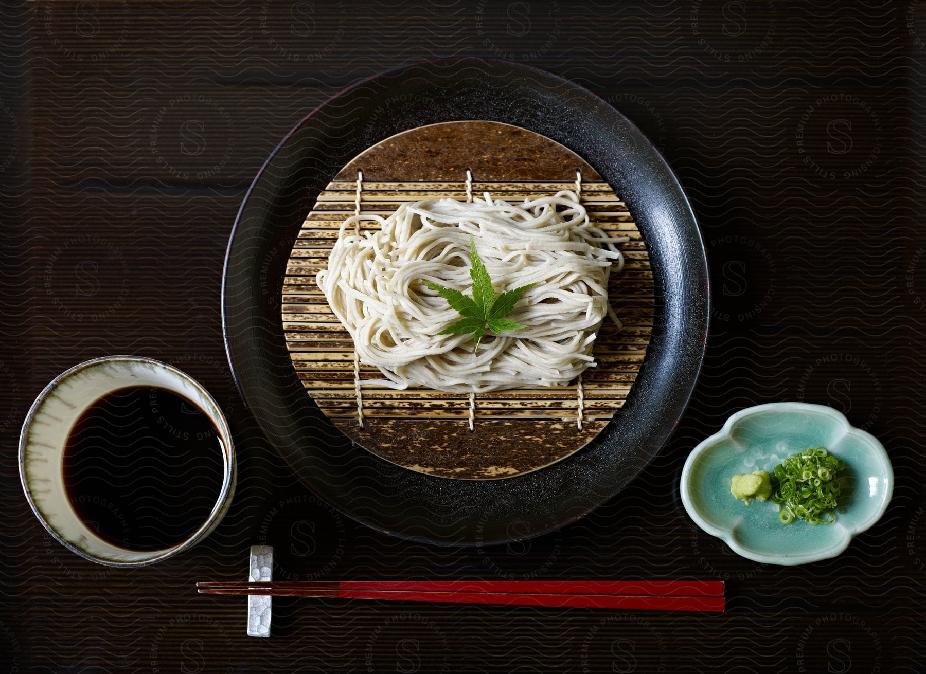 A closeup of a black plate of soba with chopsticks