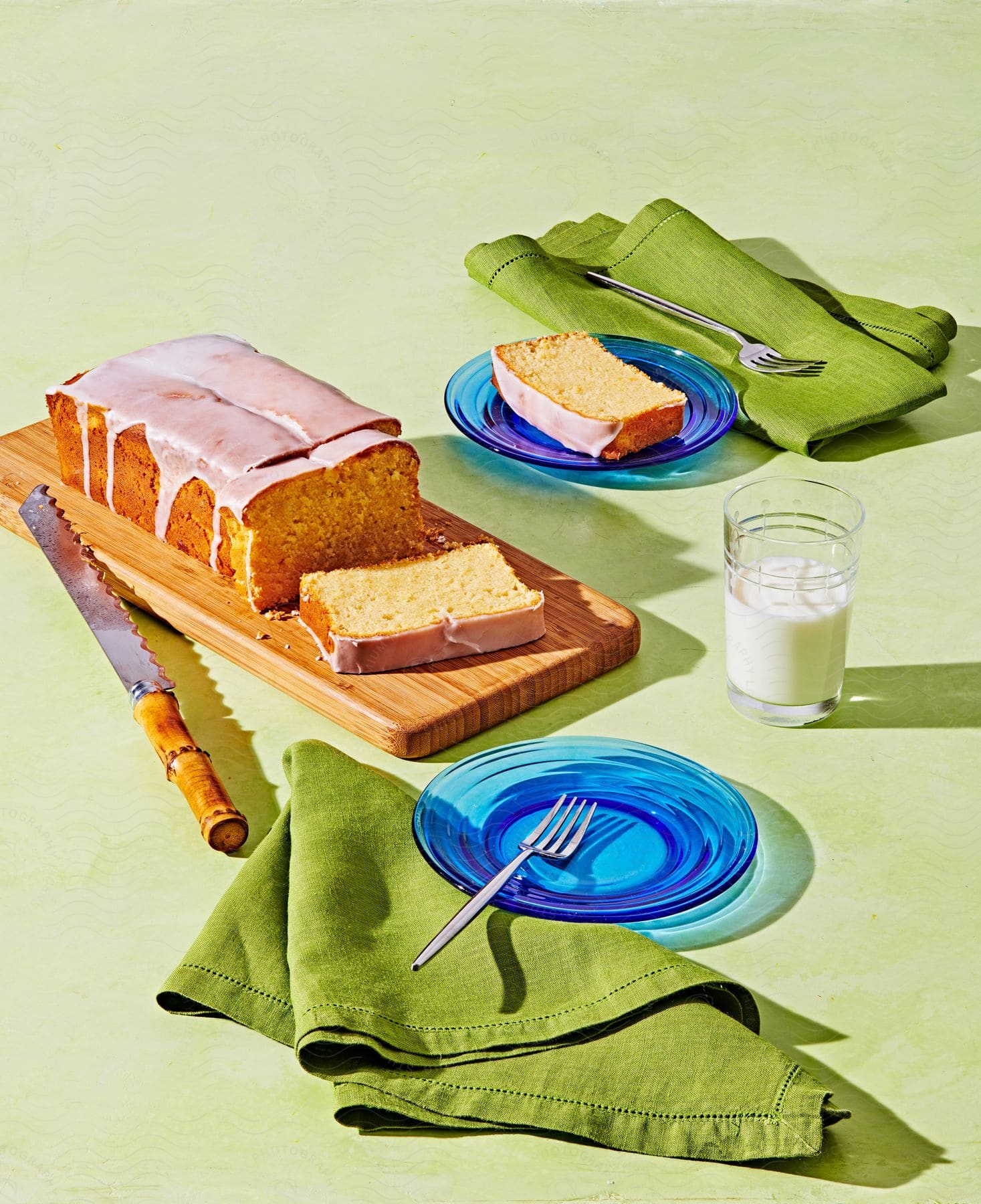 Cake on wooden surface with slice on blue plate green cloth knife and fork
