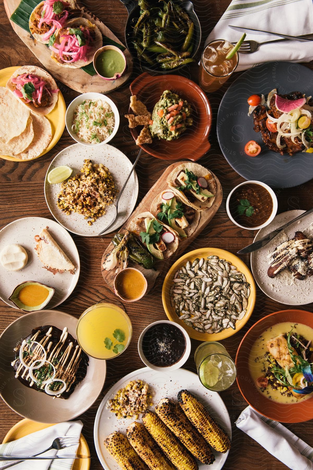 Stock photo of table filled with plates of various foods appetizers drinks and cutlery