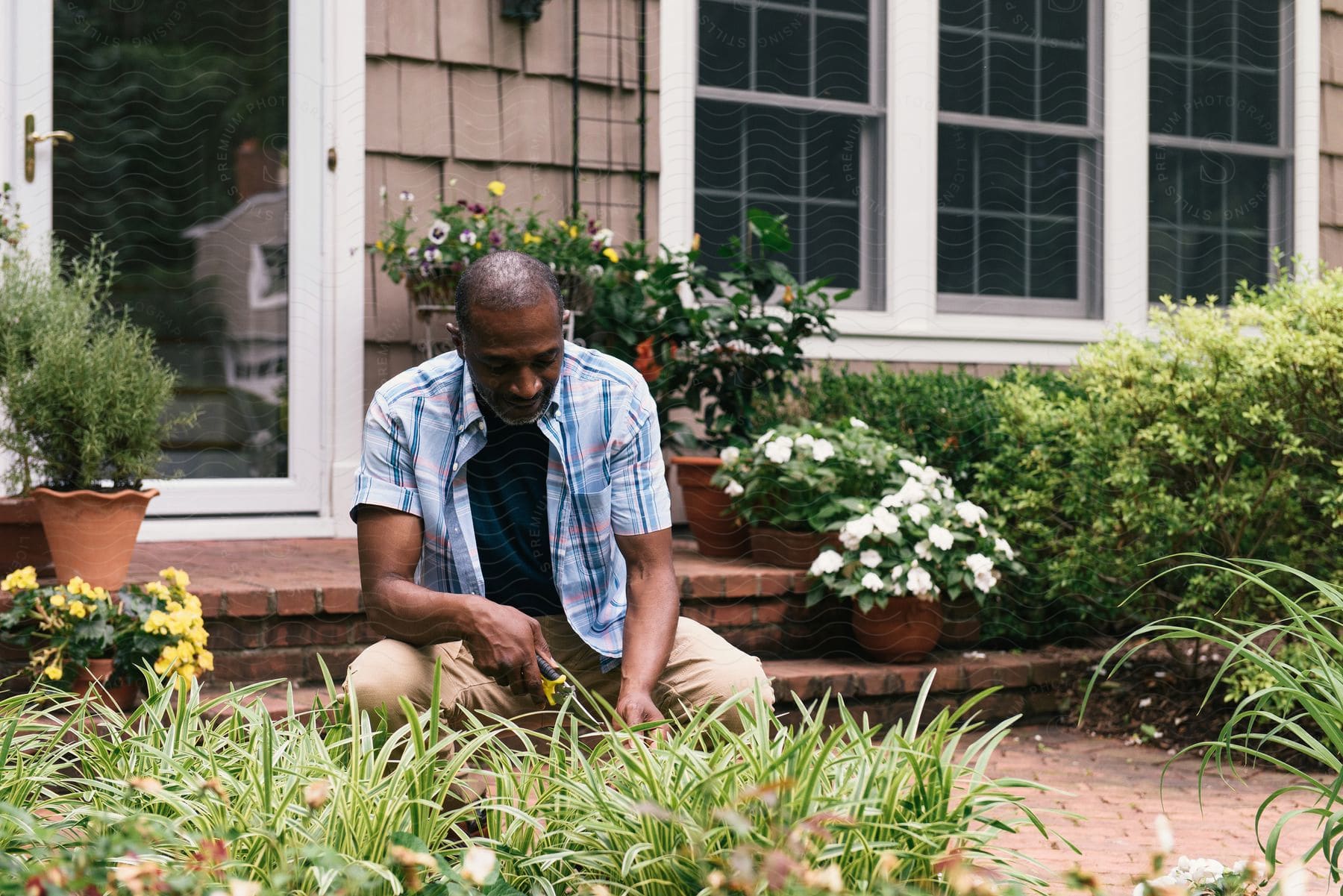 A man is tending to a garden in front of a house