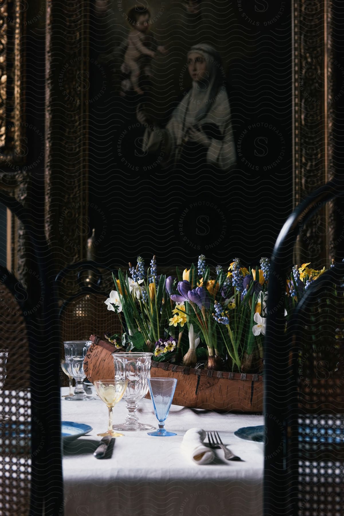 A still life featuring a table with tableware a flower arrangement and a potted plant