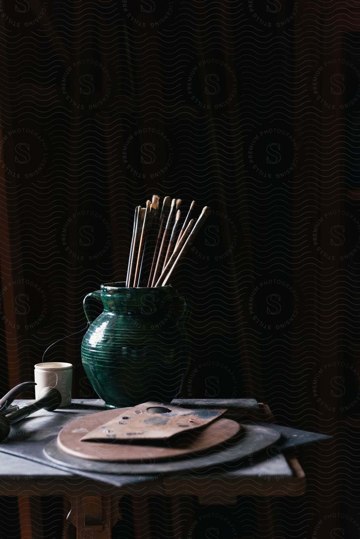 Art paint brushes on a green ceramic jar over a small table