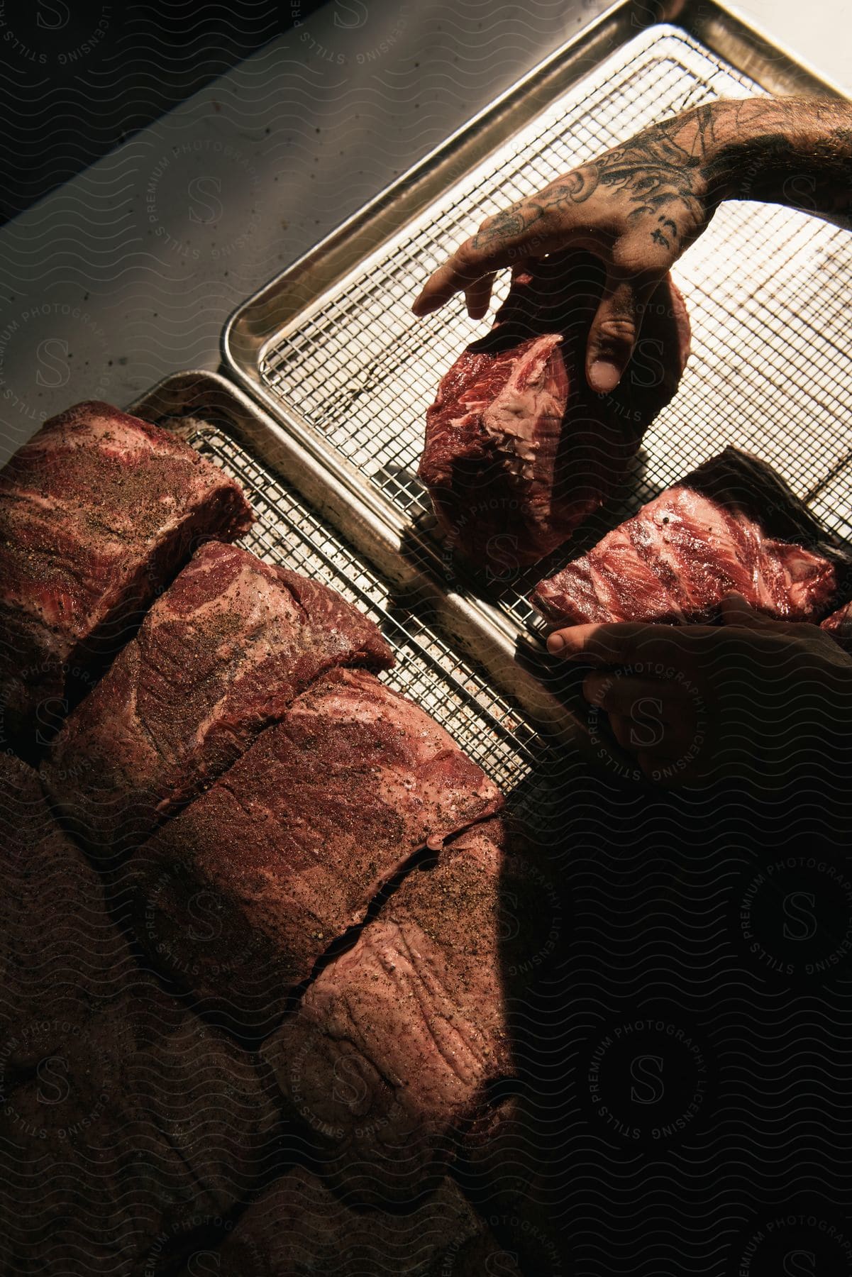 A person is seasoning pieces of meat before cooking them in the oven