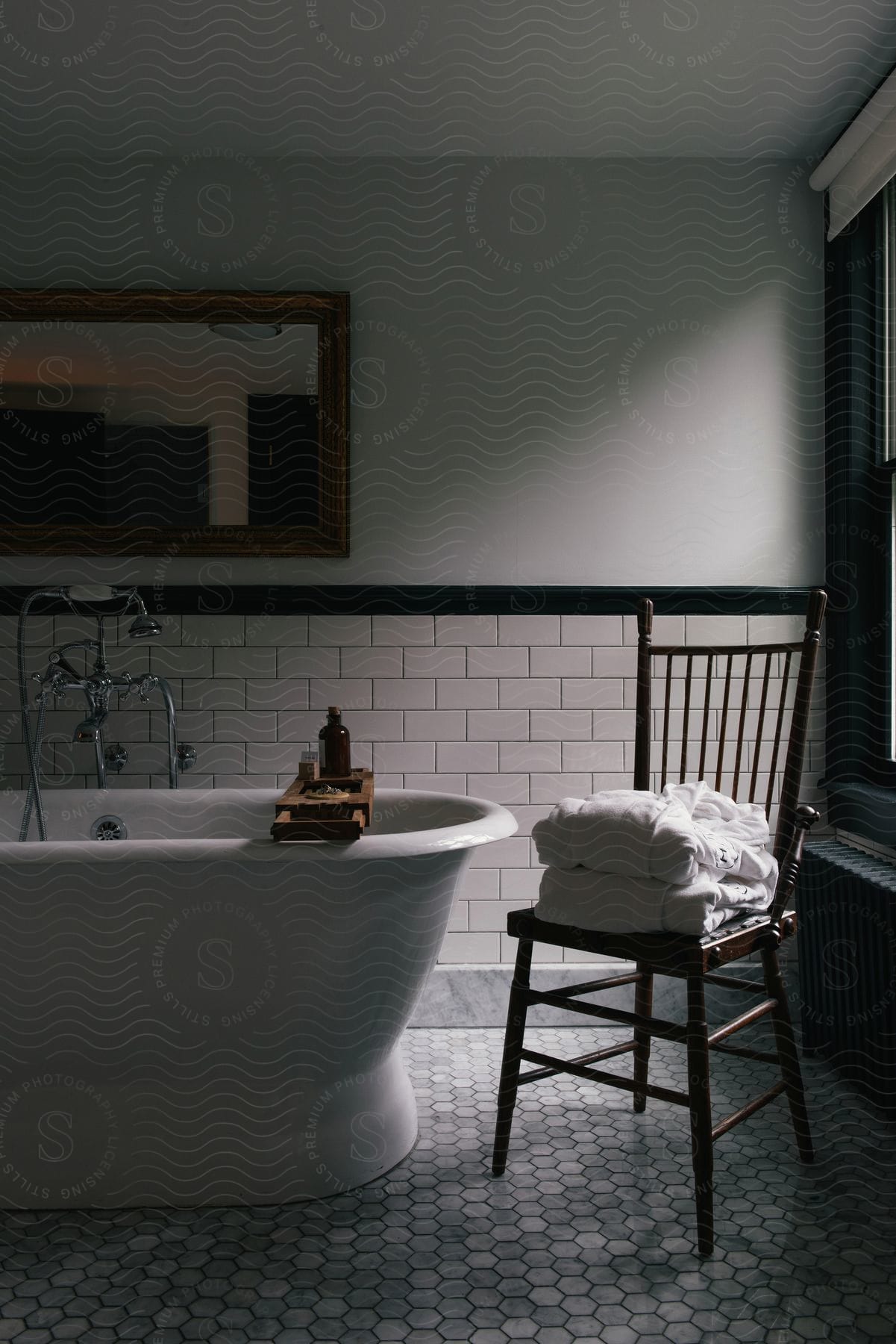 Bathroom with bathtub mirror and chair with bathrobes on top