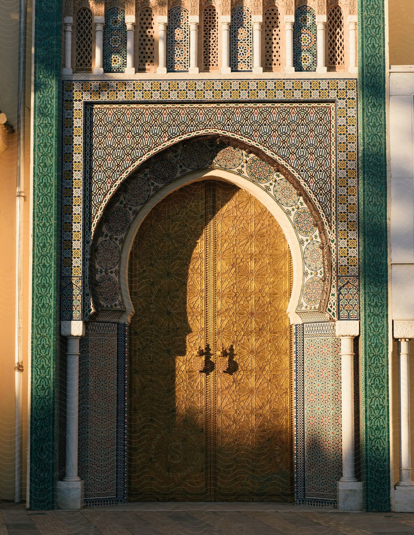 An ornate building with golden doors and detailed tiling glowing in soft sunlight