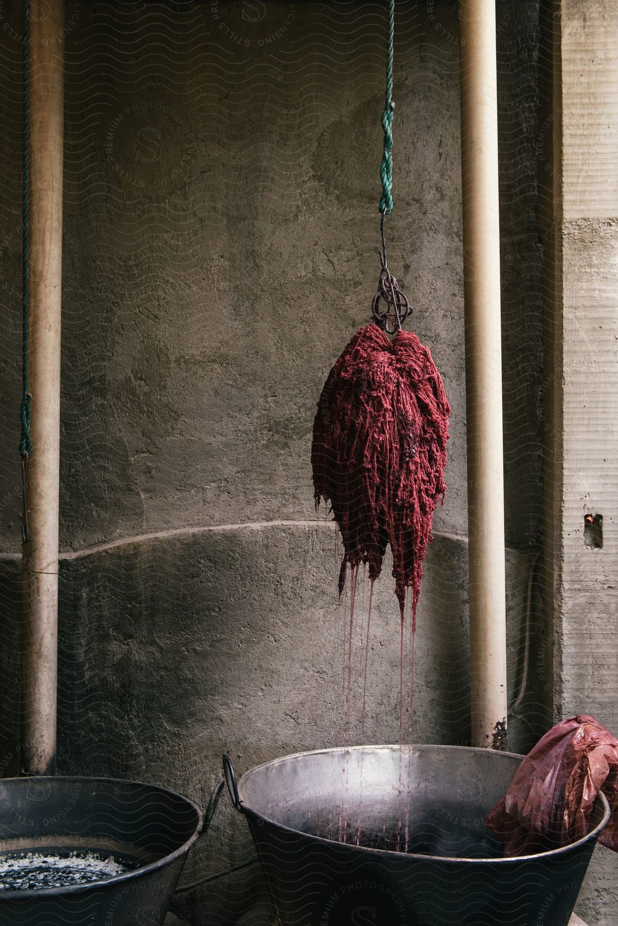 Mass of textiles hanging into dye pan near concrete wall