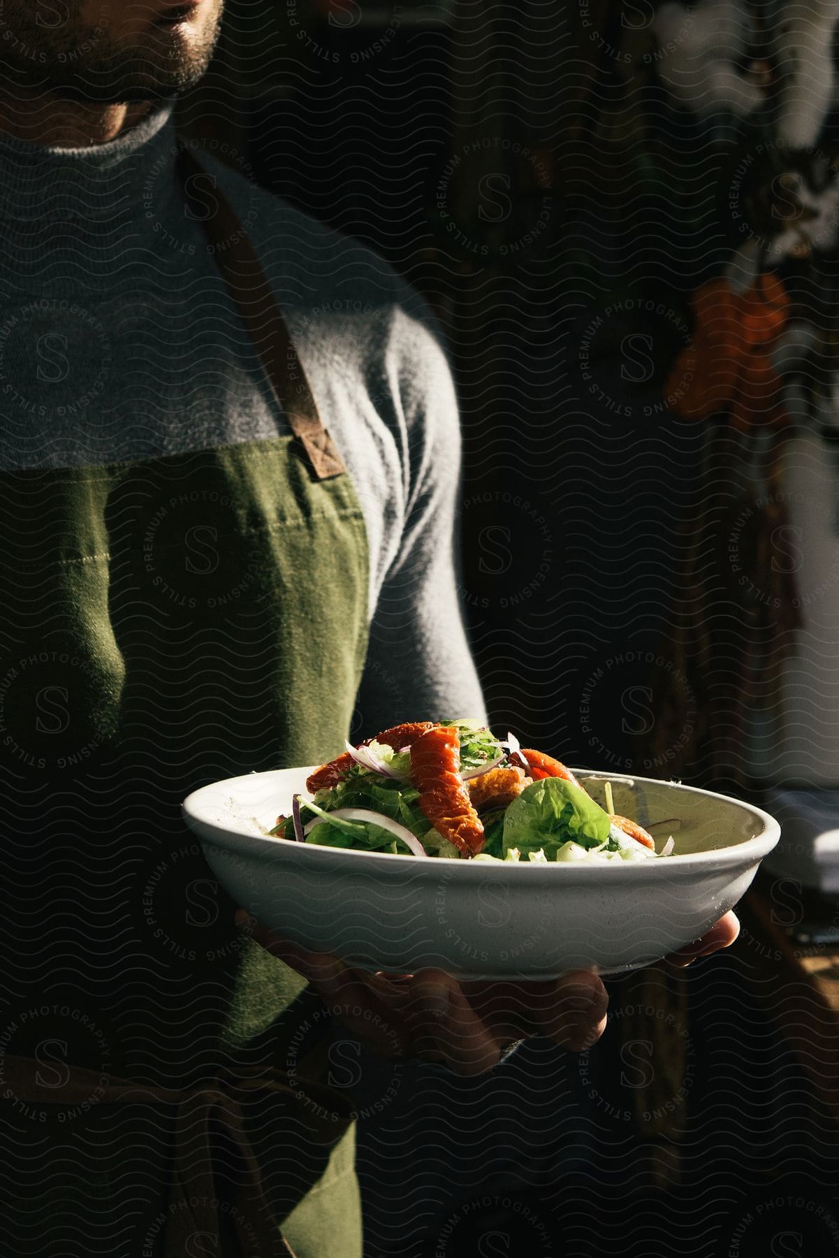 A waiter serves a main course in a large white bowl at a restaurant