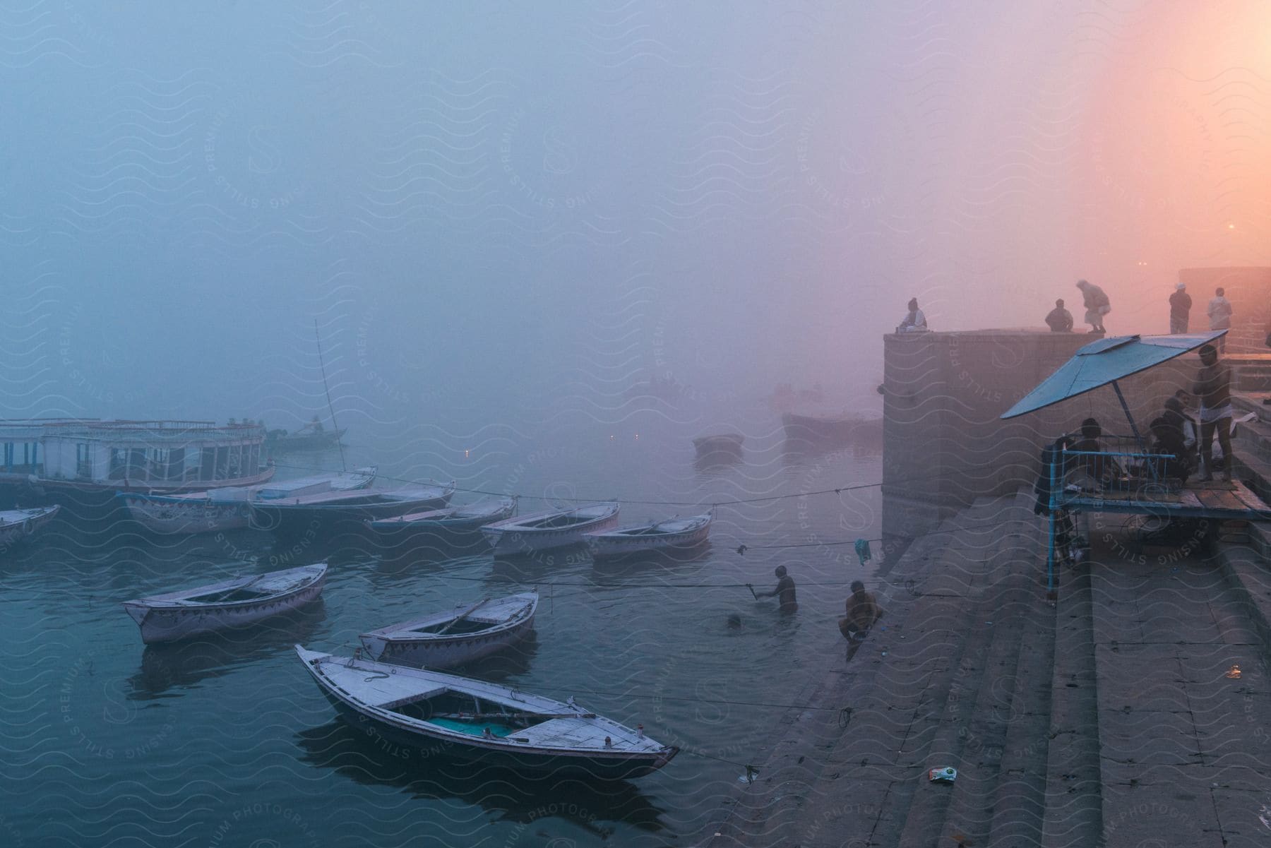 Boats on a misty lake at sunset with people in the water