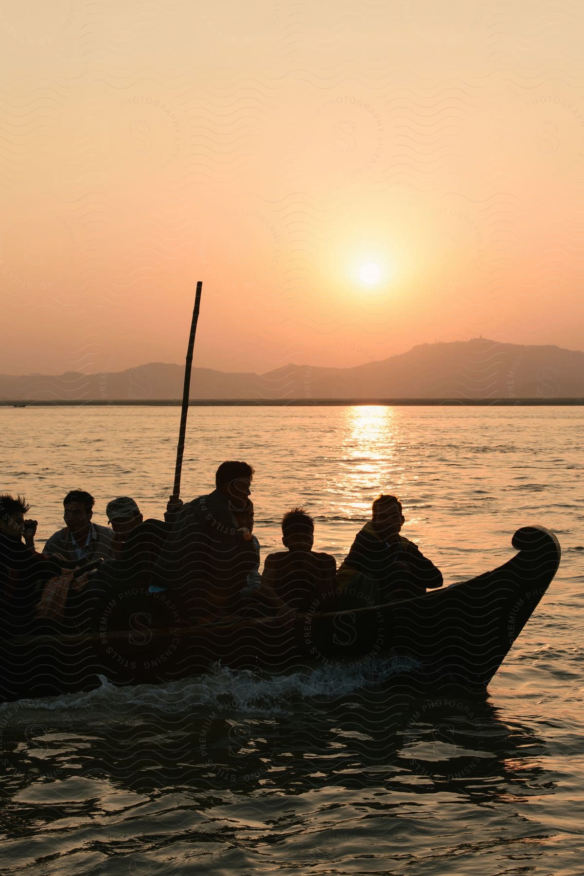 A group of men on a boat in the ocean with mountains in the distance