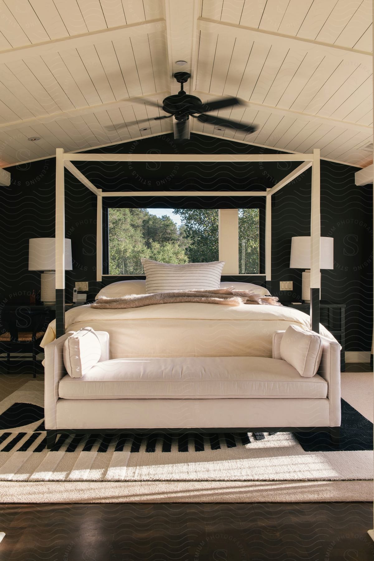 A bedroom with modern decor featuring a bed wood flooring a window and a ceiling fan