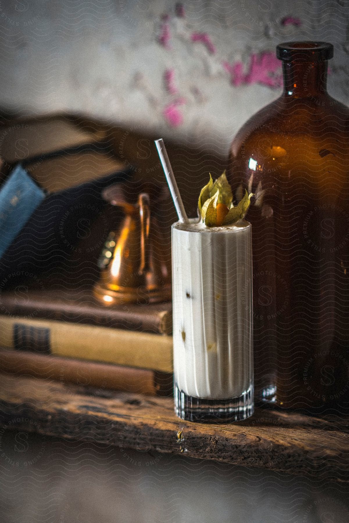 A cream based cocktail on a wooden shelf next to books and a bottle