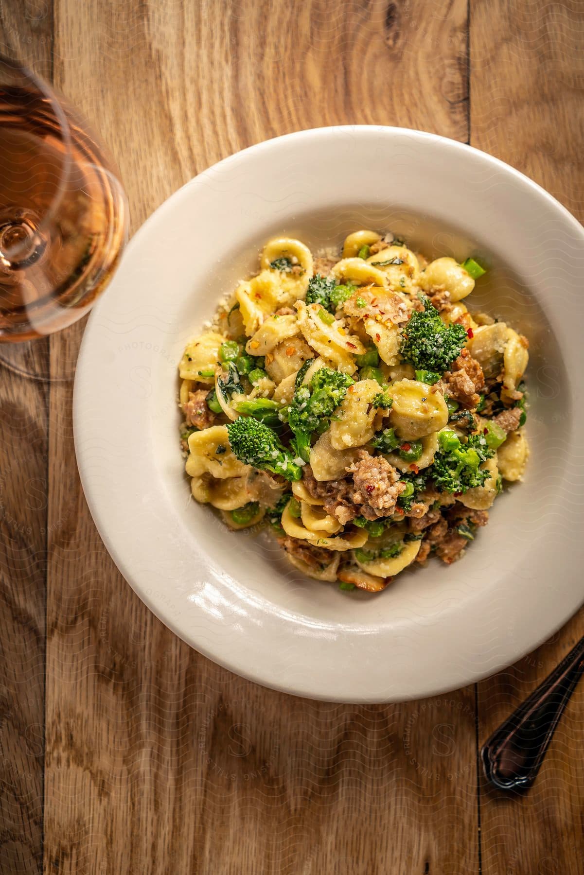 A pasta dish with broccoli and a glass of wine