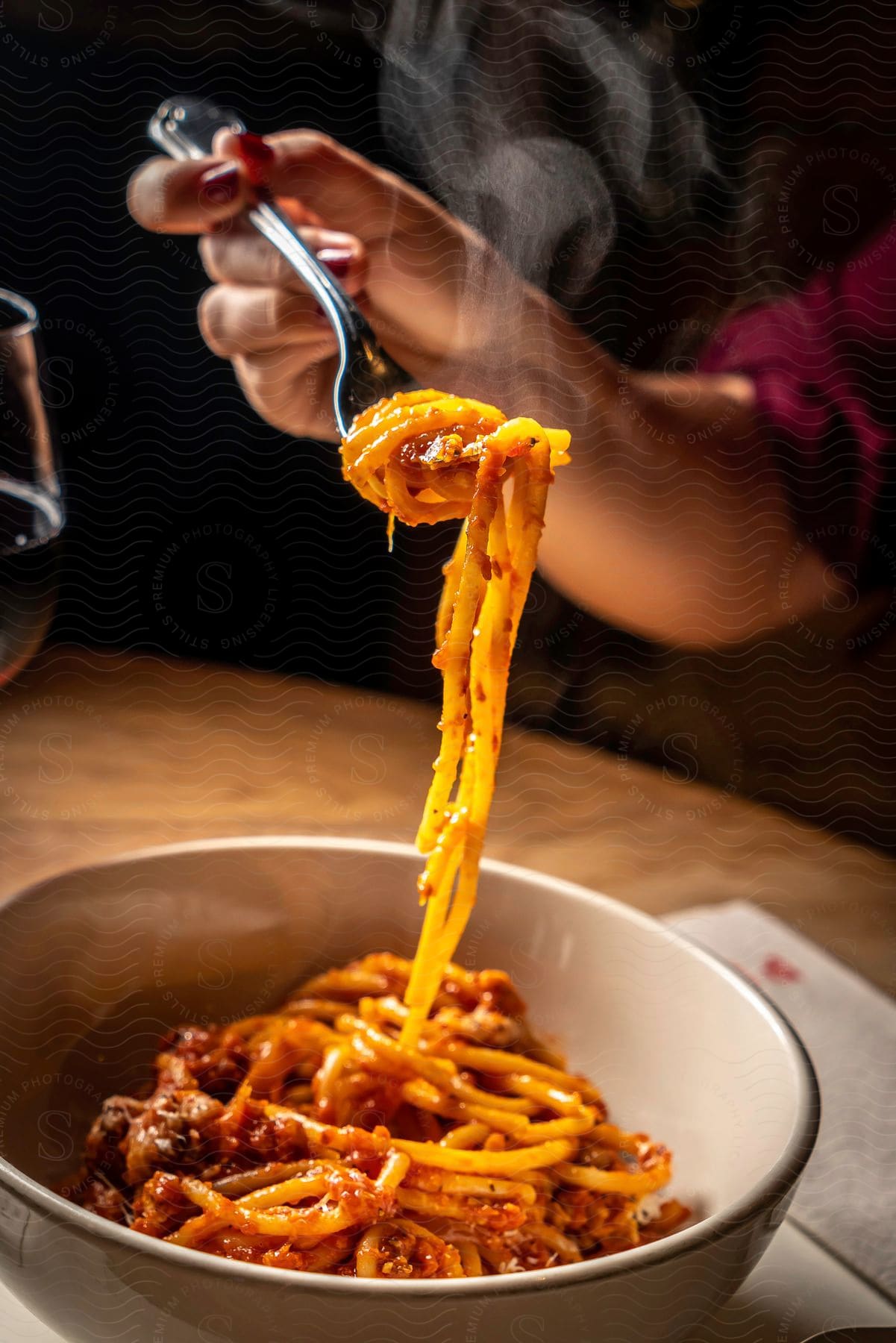 Stock photo of a woman twirling pasta with a fork while eating at a restaurant