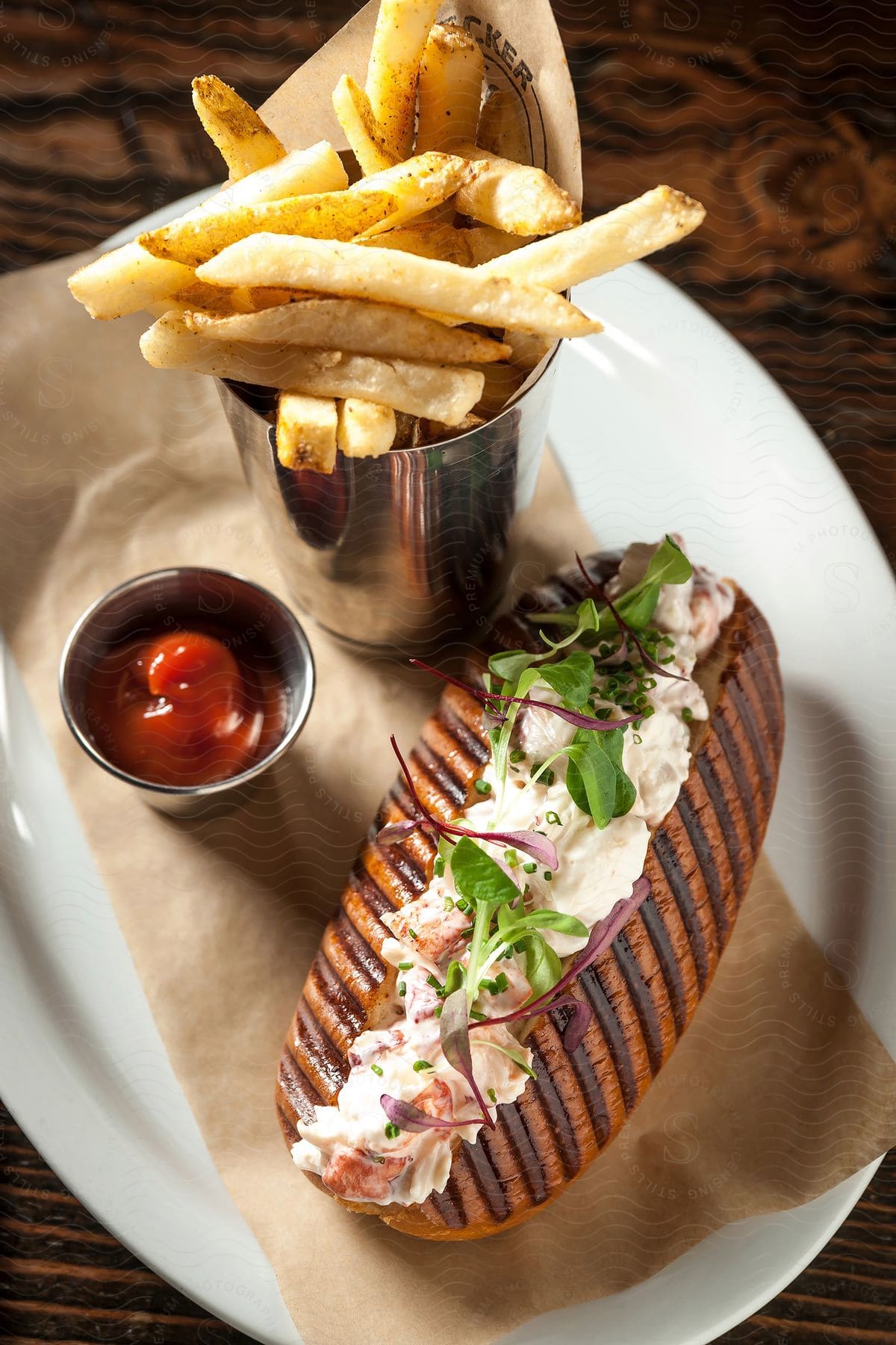 A sandwich french fries and ketchup are arranged on a white oval plate