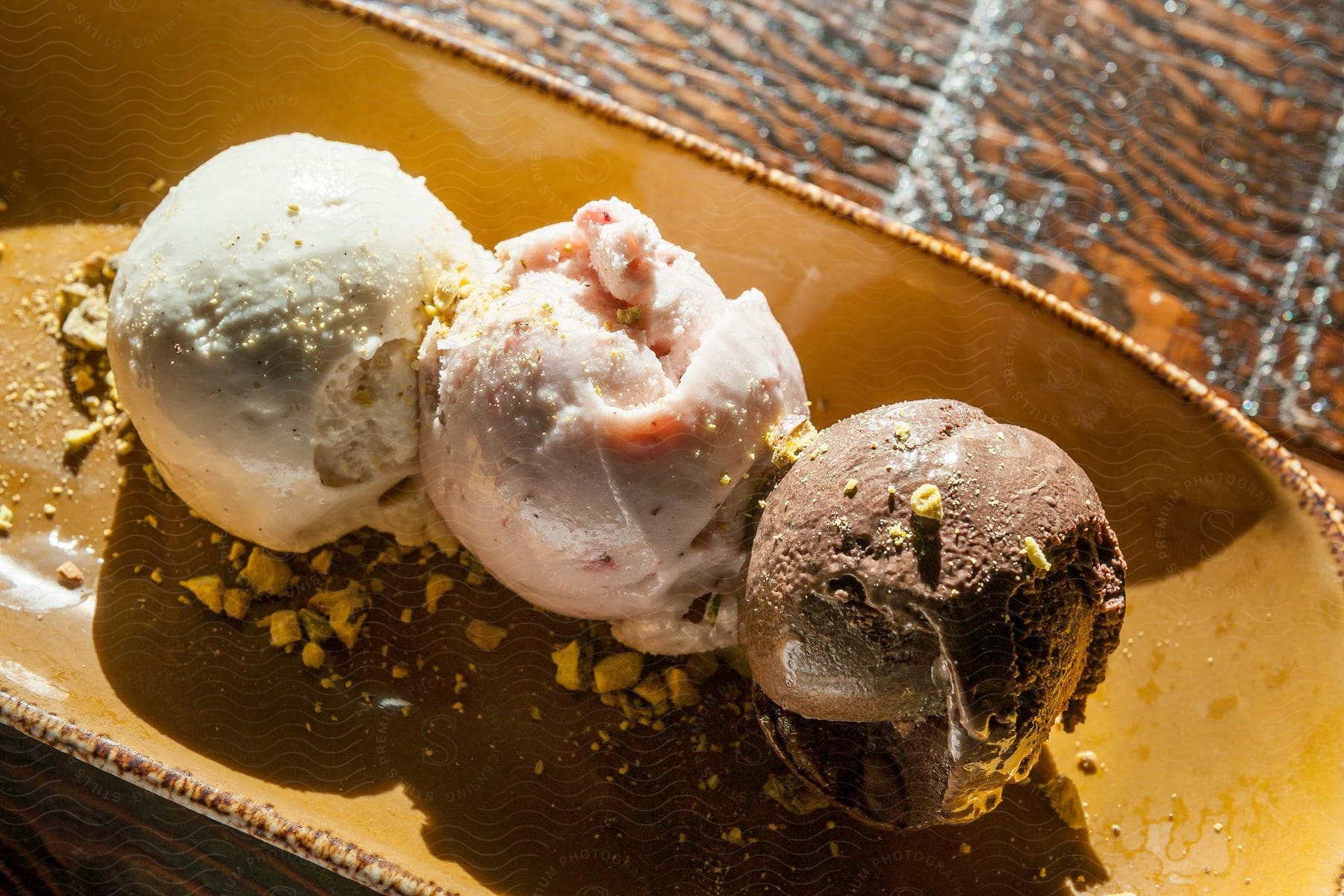 A table with a yellow bowl holding three scoops of ice cream topped with nuts