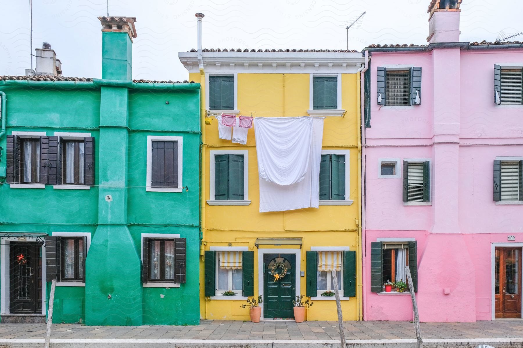 Teal pink and yellow concrete apartment houses along an italian waterway on a cloudy day