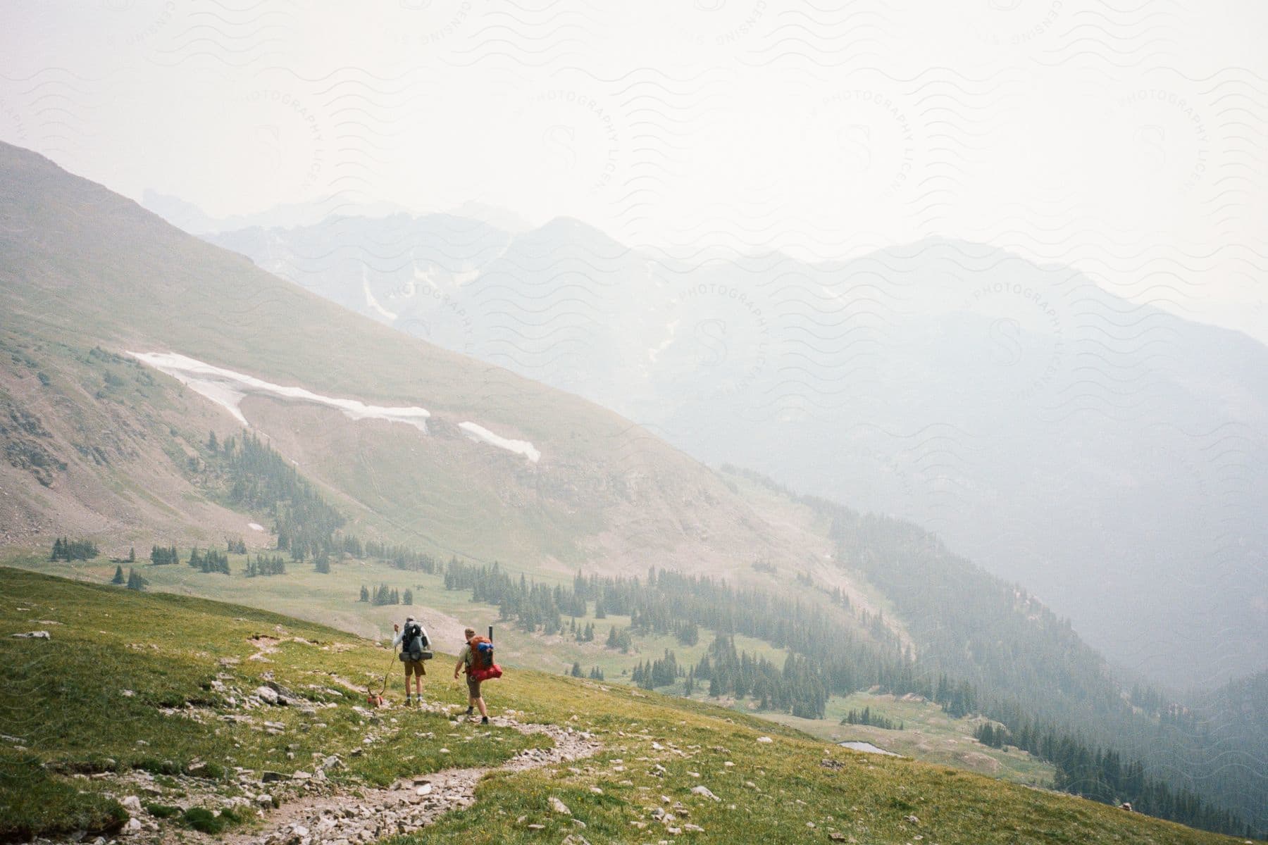 Two hikers ascending a mountain trail with large backpacks